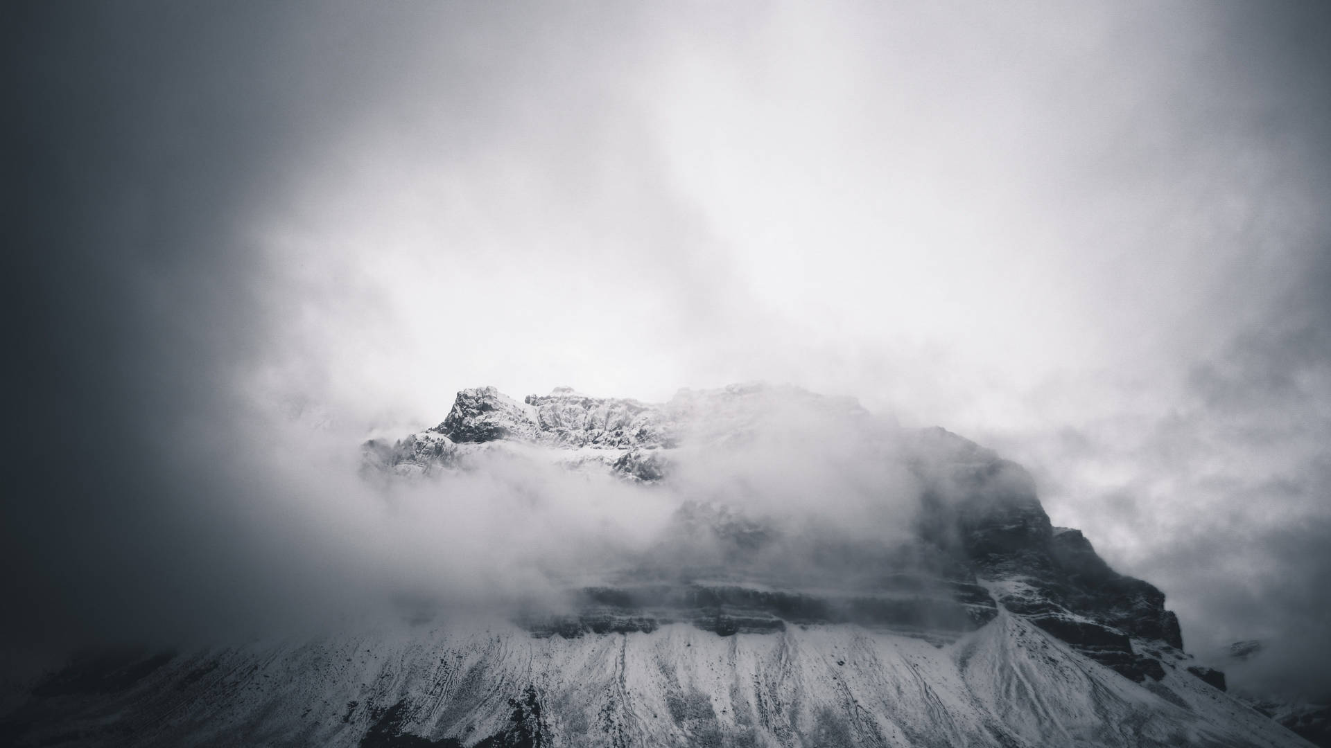 白雪覆蓋的山峰在暴風雨的天空中穿過厚厚雲層聳立。