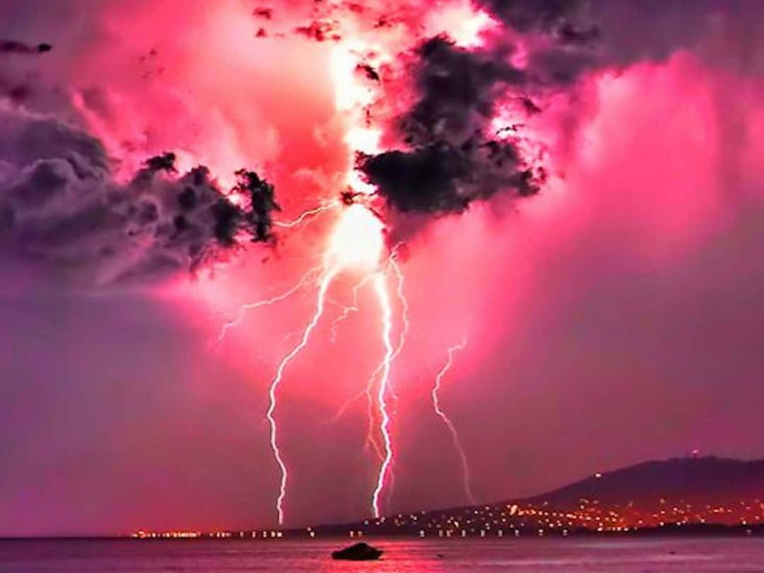 陰鬱傍晚天空的戲劇性暴風雨場景 壁紙 — 一場戲劇性的粉紅色雷暴照亮了夜晚的海岸城市，生動的電光劃破天空。