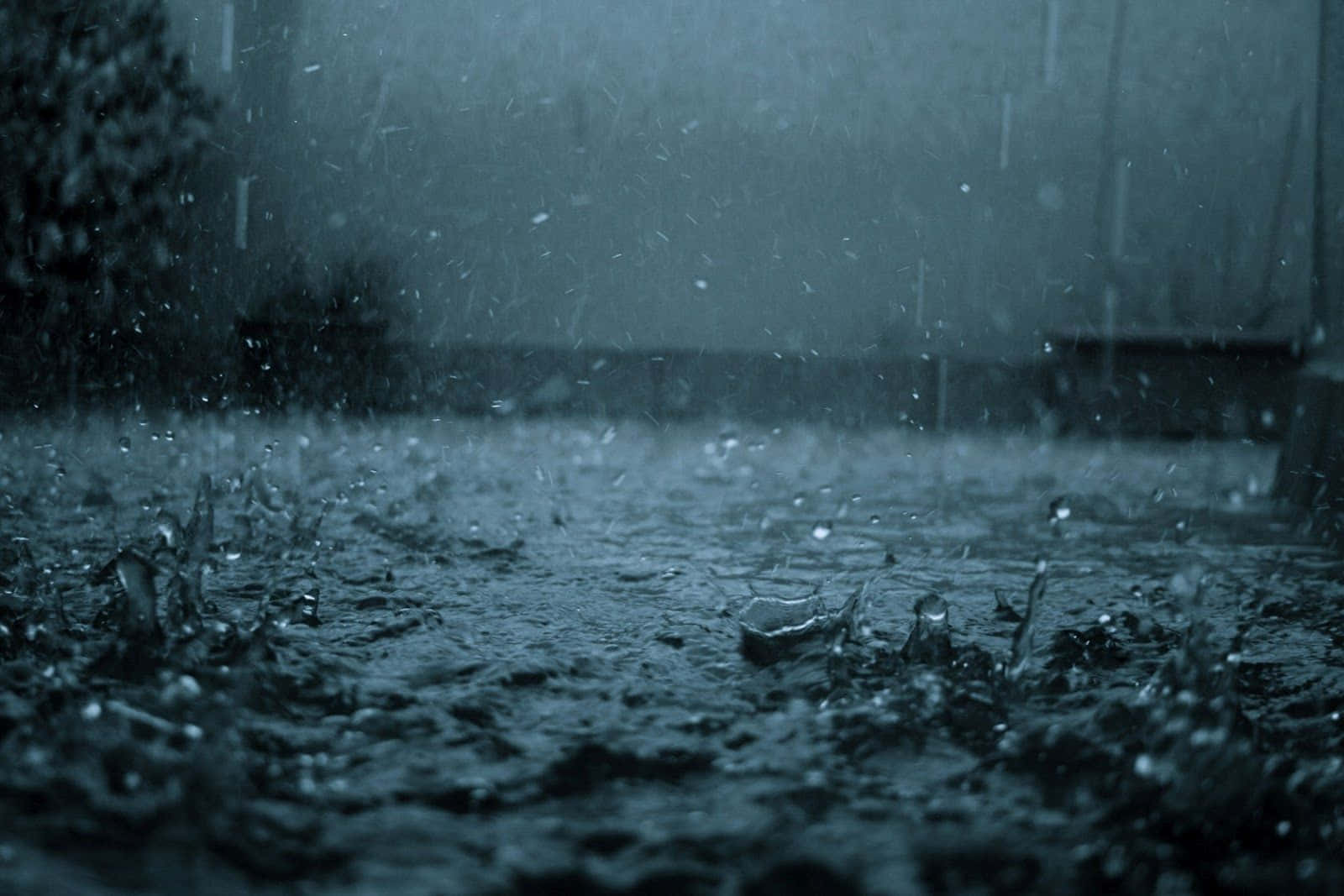 陰鬱暴雨憂傷背景 壁紙 — 沉重的雨滴在陰沉的灰色天空下戲劇性地濺在濕漉漉的路面上。