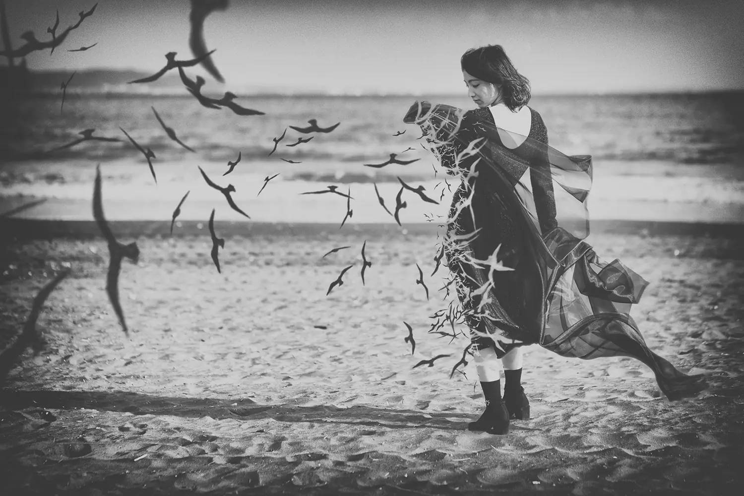 海灘上的女士，鳥兒在她周圍盤旋，單色