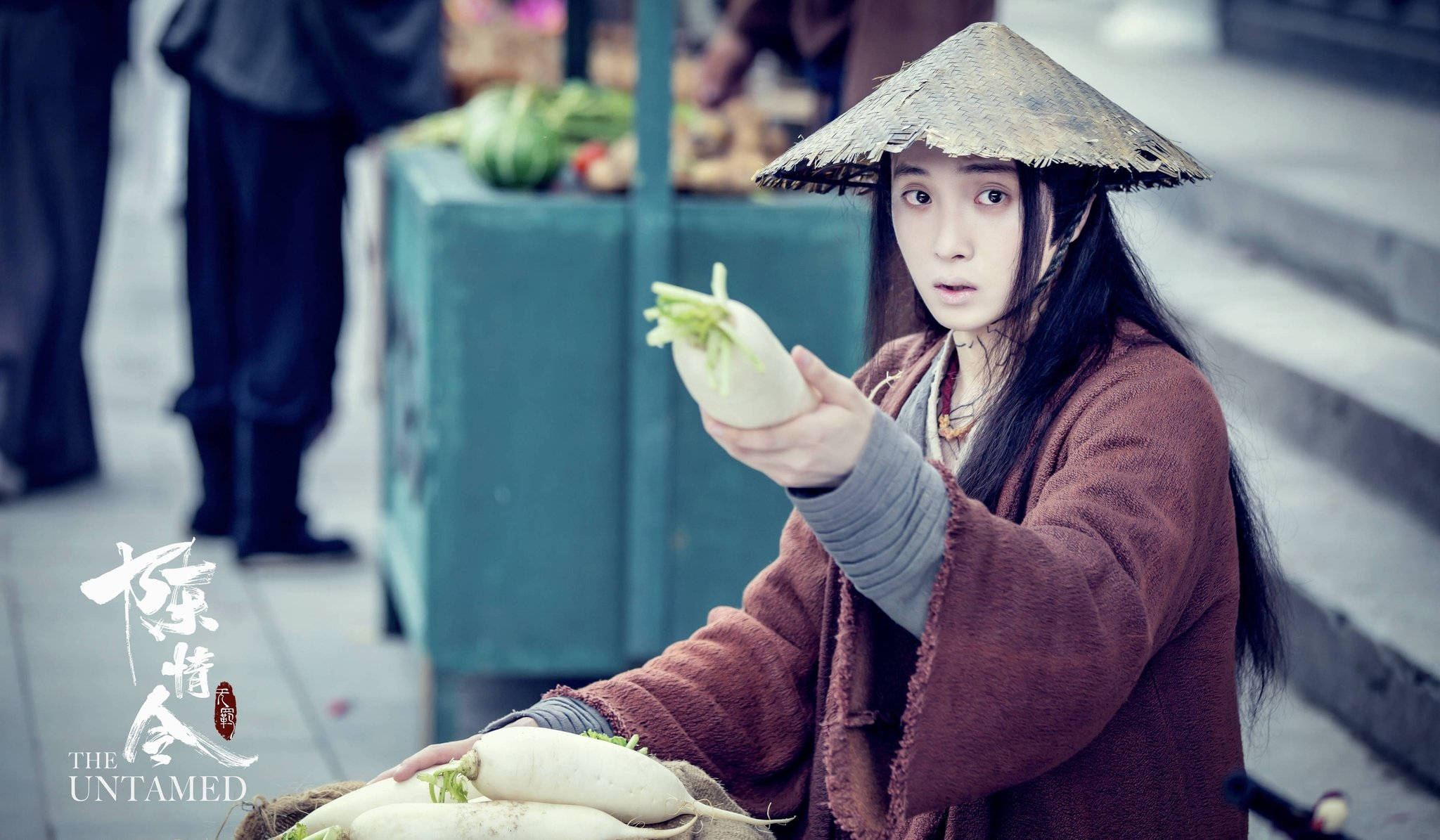 《陳情令》可愛溫寧 壁紙 — 一個戴草帽嘅人喺一個有綠色農產品同模糊人影嘅市場攤位度拎住一個白蘿蔔。
