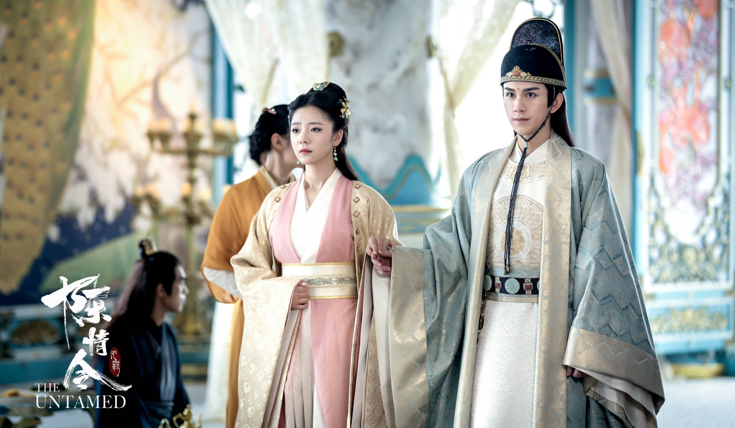 《陳情令》蘭陵金氏 壁紙 — 一男一女身穿華麗的傳統長袍，站在裝飾華麗的宮殿大廳中，牆上有精緻的壁畫和金色燭台。