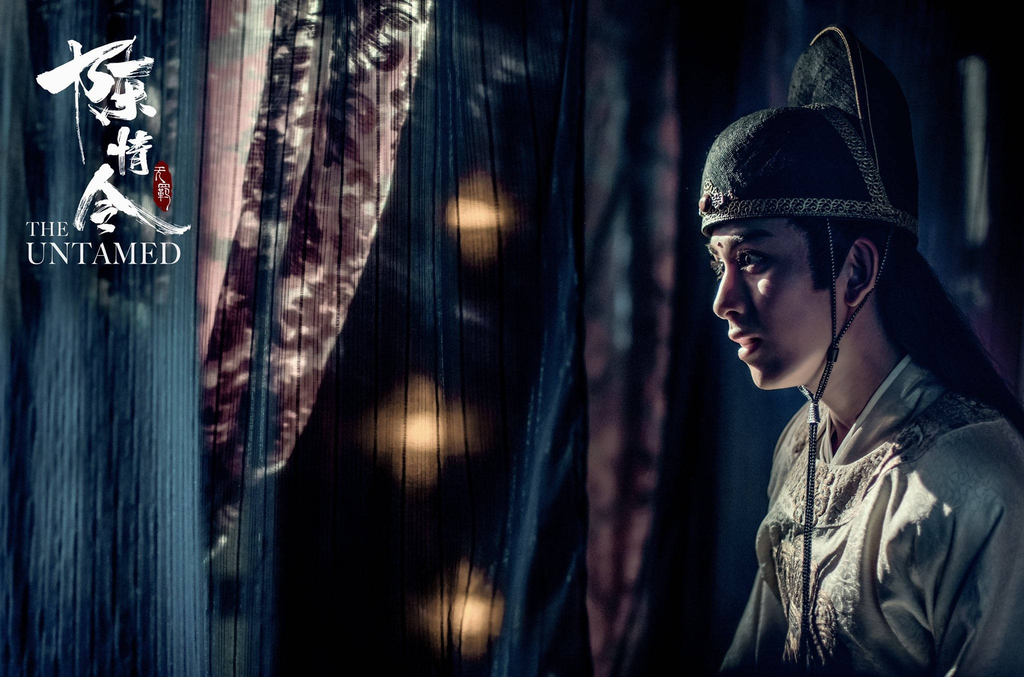 《陳情令》金光瑤報仇 壁紙 — 一位身穿傳統中式長袍的年輕男子在昏暗的房間裡透過厚重的窗簾若有所思地凝視著。