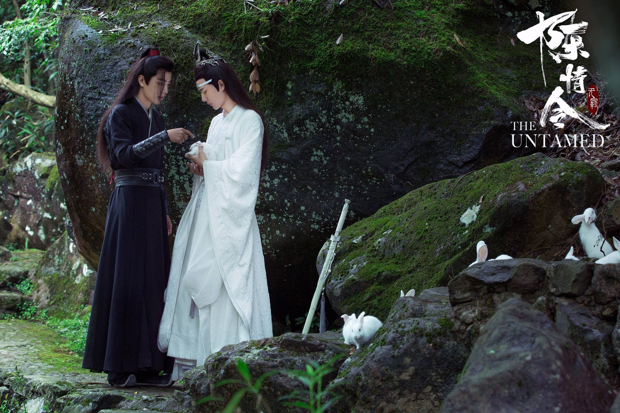 《陳情令》魏無羨與兔子 壁紙 — 兩個穿著傳統長袍的人物站在長滿苔蘚的森林空地中，白兔聚集在他們腳邊。