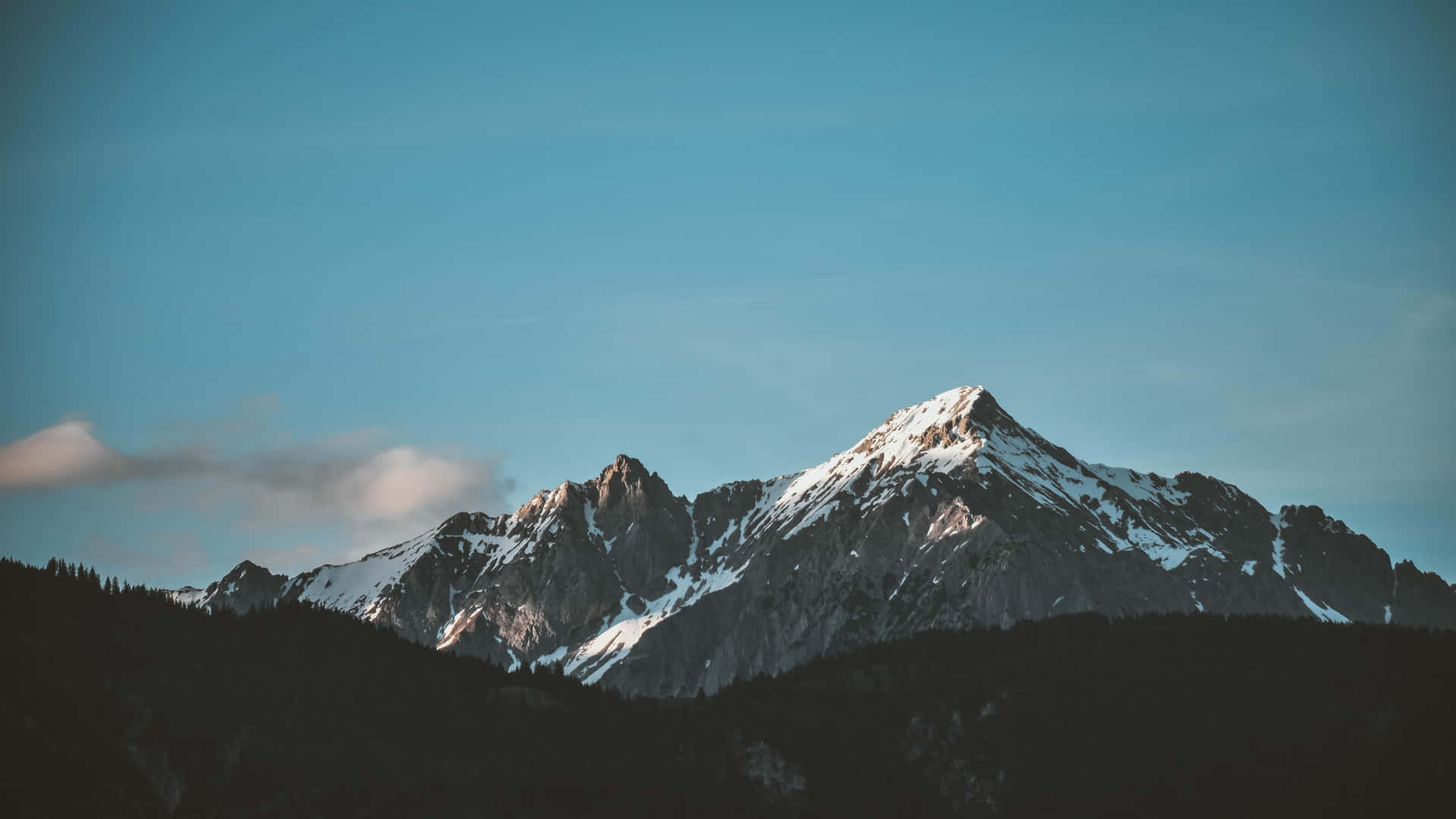 雪山峰在清澈藍天下，雲朵飄浮。
