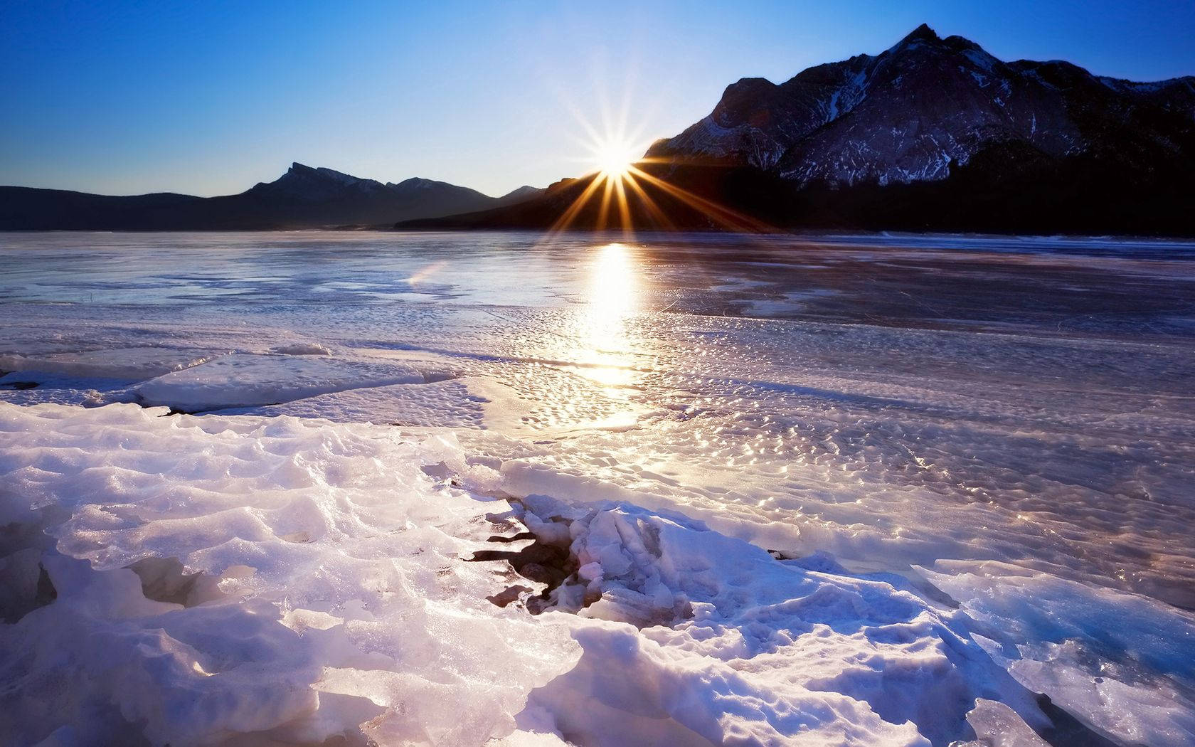春季 桌布 壁紙 — 陽光在冰湖上閃耀，雪山在清澈的藍天下。