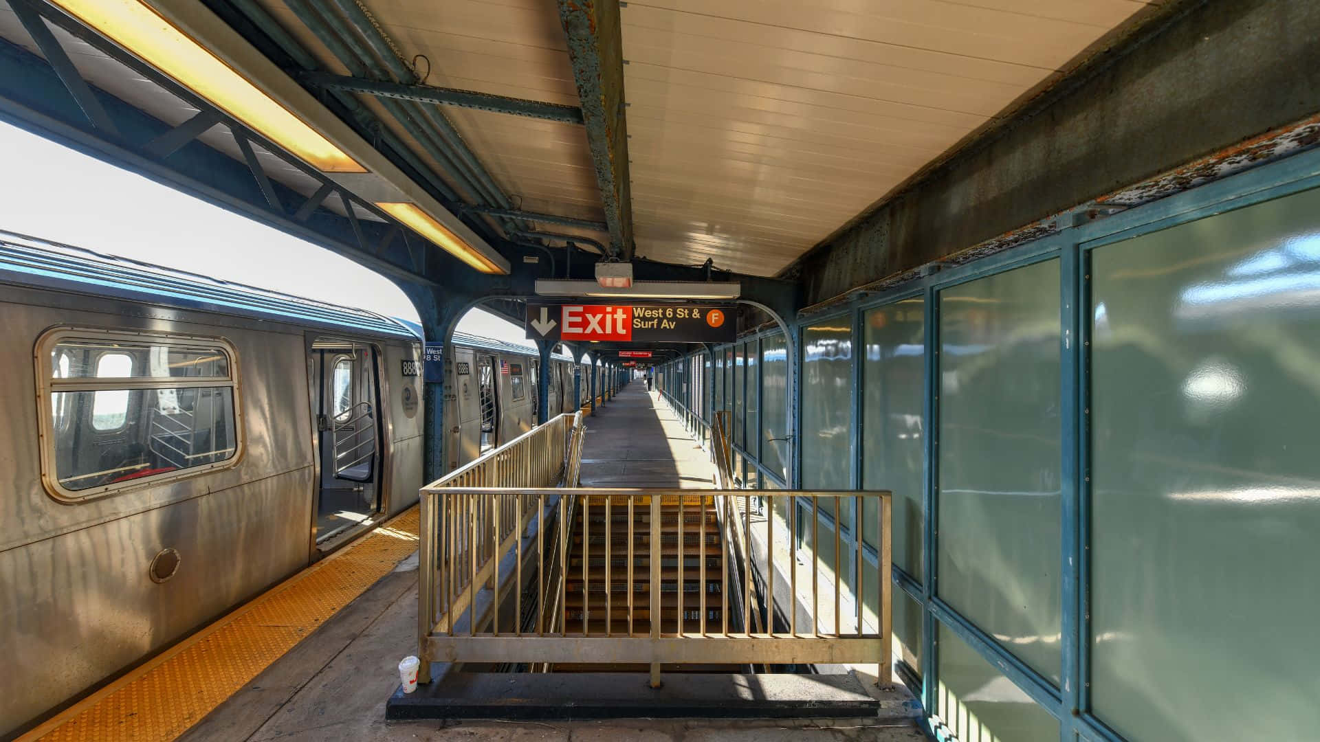 Subway 桌布 壁紙 — 陽光普照的地鐵月台，列車停靠在車站，頭頂上可見出口標誌。