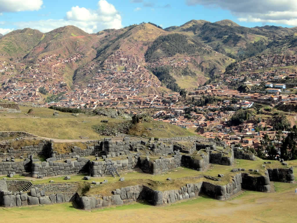 古代印加石遺跡，山腰上有現代城鎮，天空晴朗。