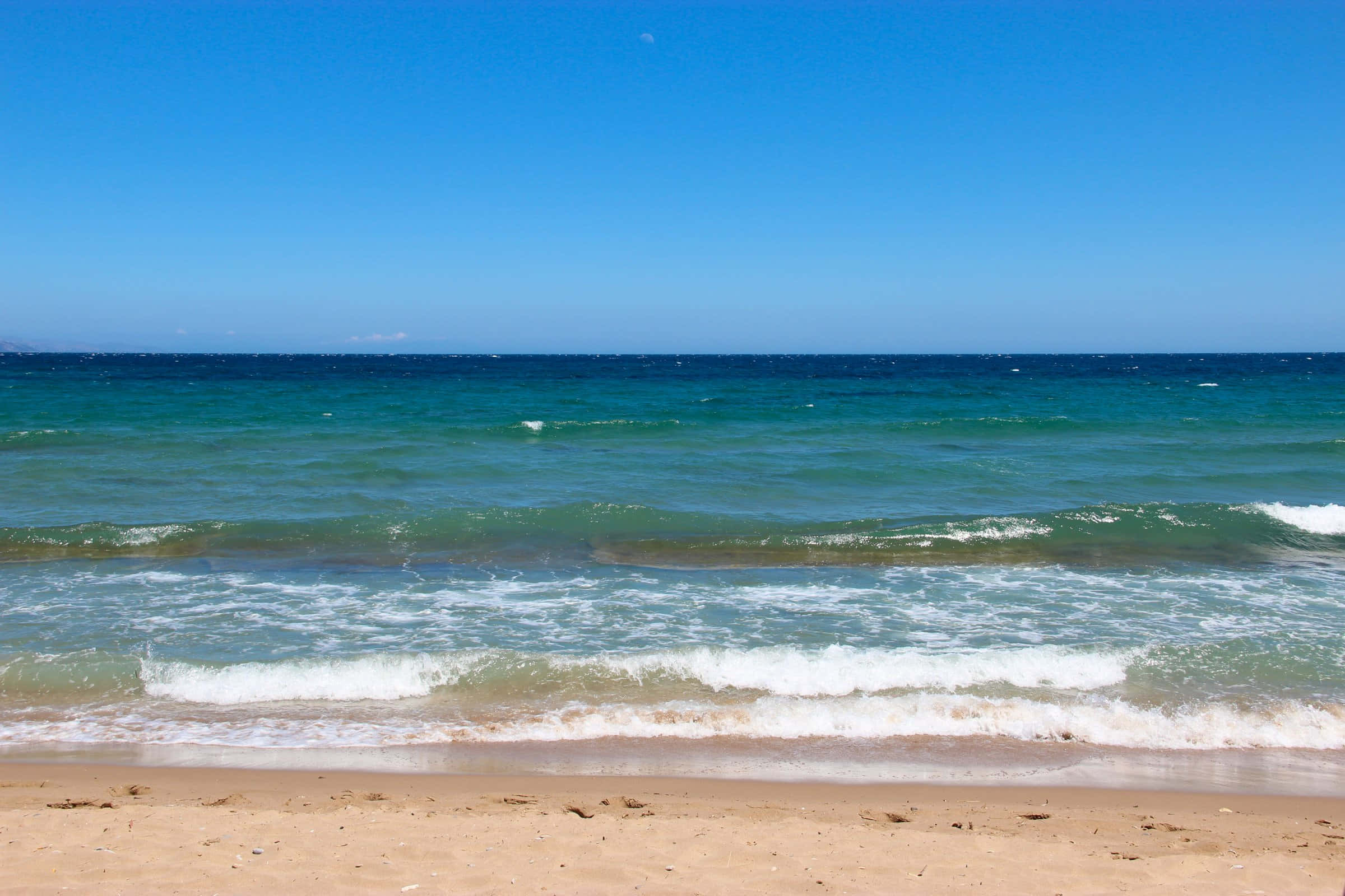 Beach Waves 桌布 壁紙 — 陽光照射下的碧綠海浪拍打著金色沙灘，天空清澈湛藍。
