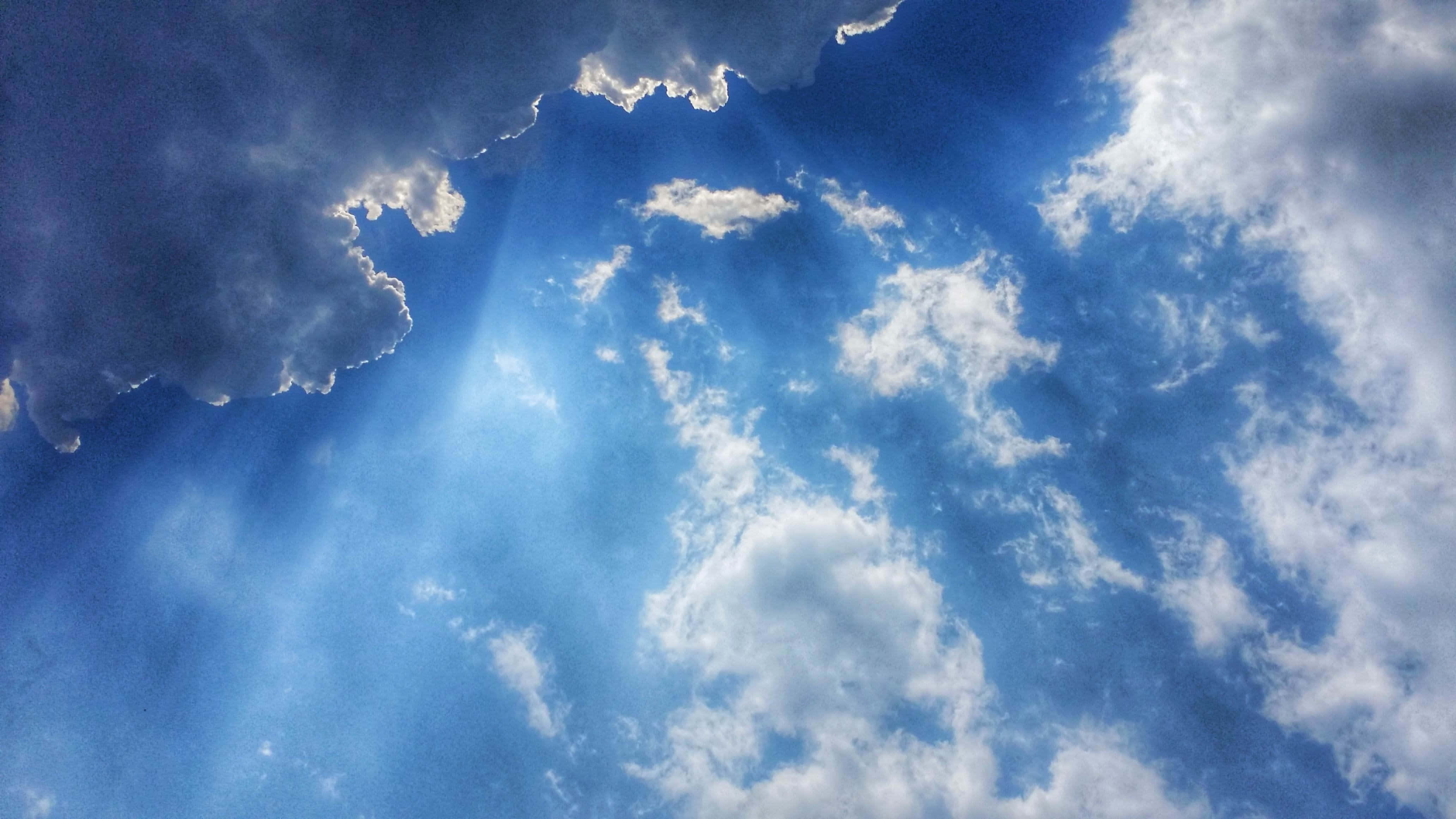 Blue Skies 桌布 壁紙 — 陽光穿透戲劇性的雲層，映襯著充滿活力的藍天，營造出神聖而令人敬畏的景象。