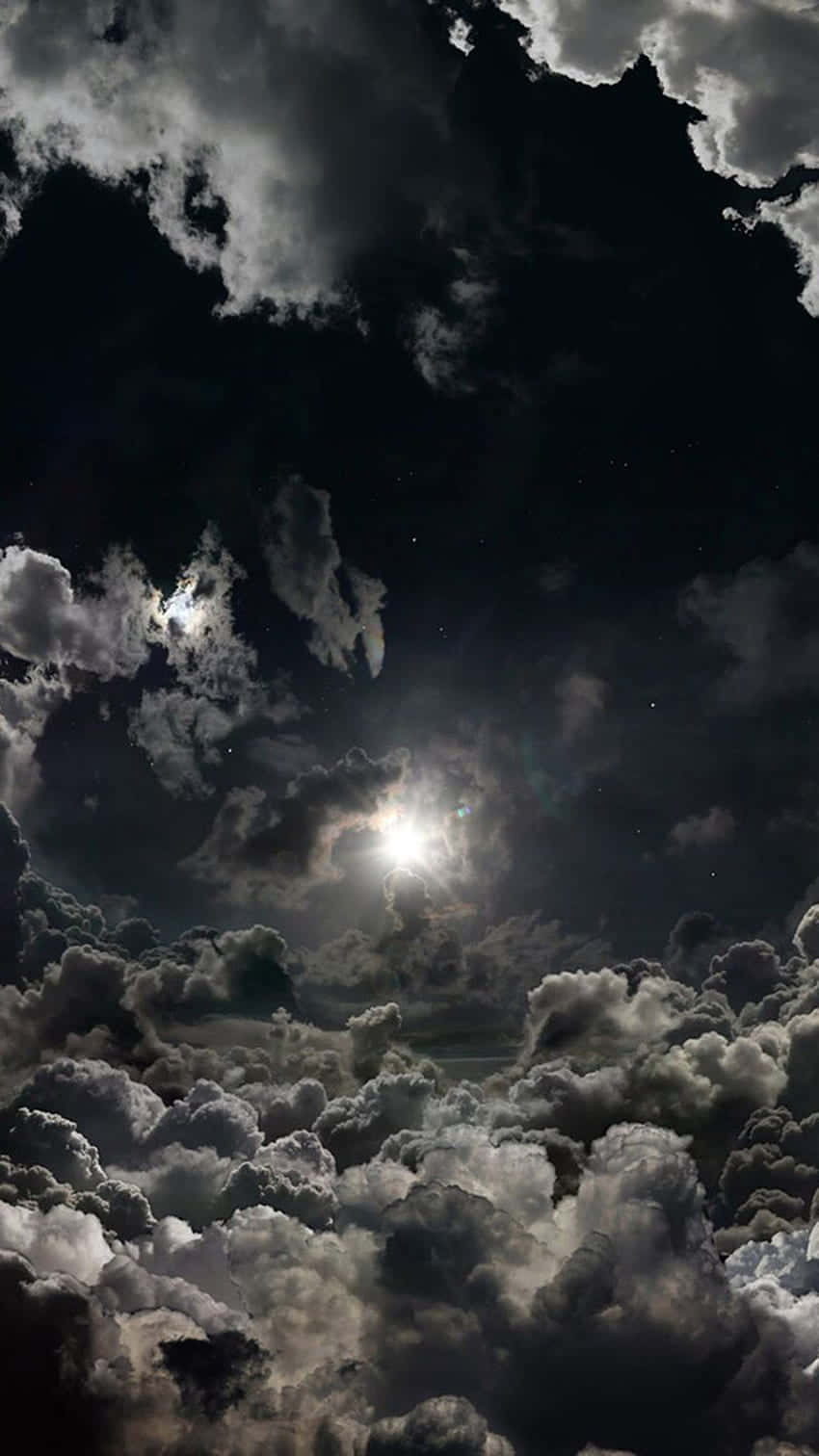 月亮透過烏雲照耀，夜空中可見星星。