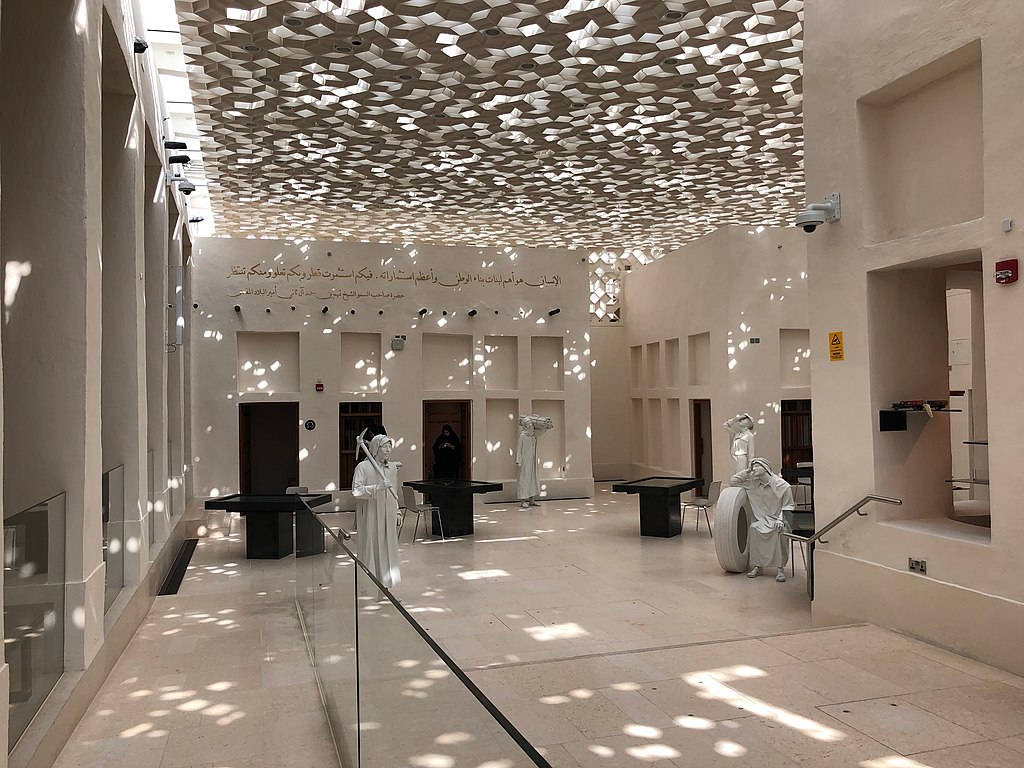 Qatar 桌布 壁紙 — 陽光穿過幾何天花板，在現代博物館大廳的白色大理石地板和雕像上投下斑駁的陰影。