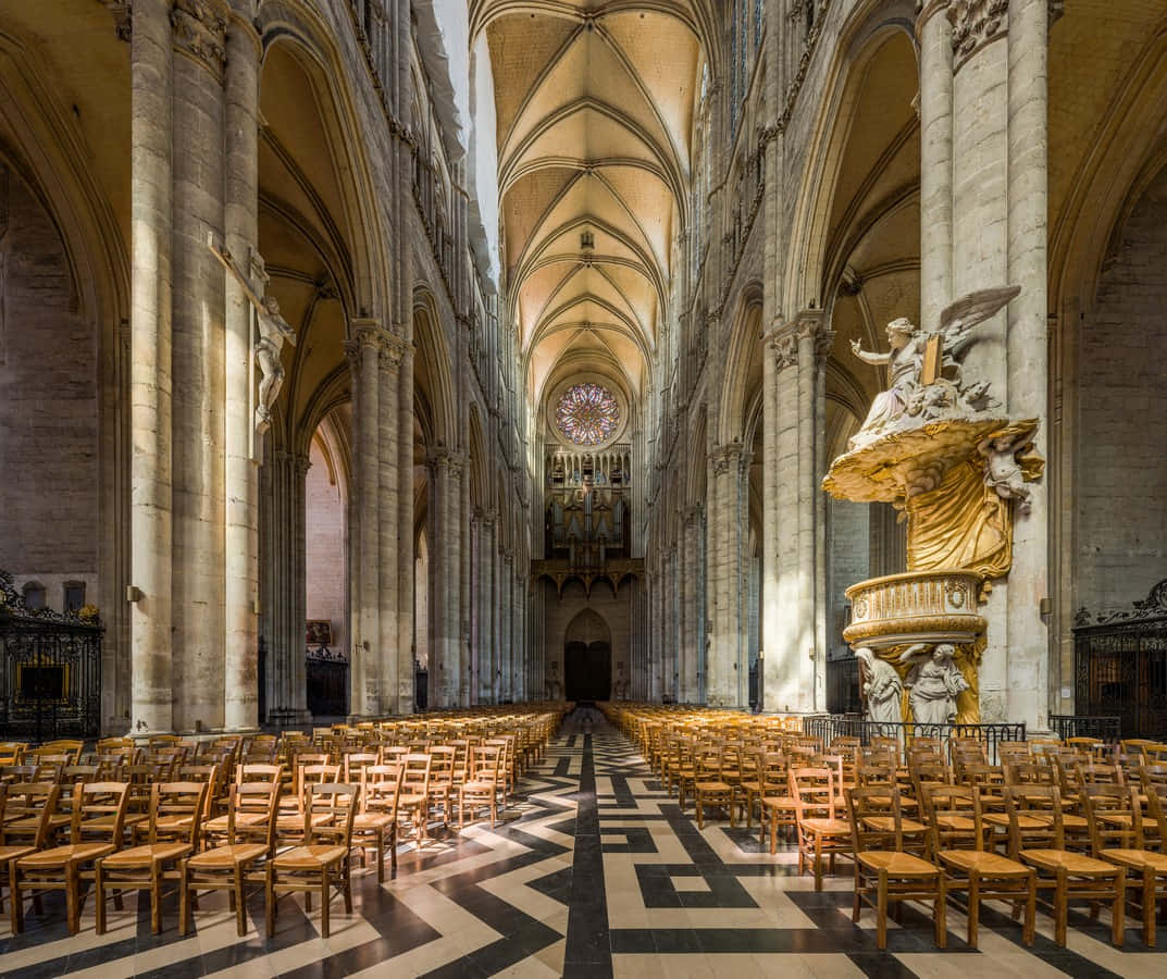 Gothic Architecture 桌布 壁紙 — 陽光穿過玫瑰窗，照亮了宏偉哥德式大教堂內一排排的木椅，教堂有拱形天花板和石柱。
