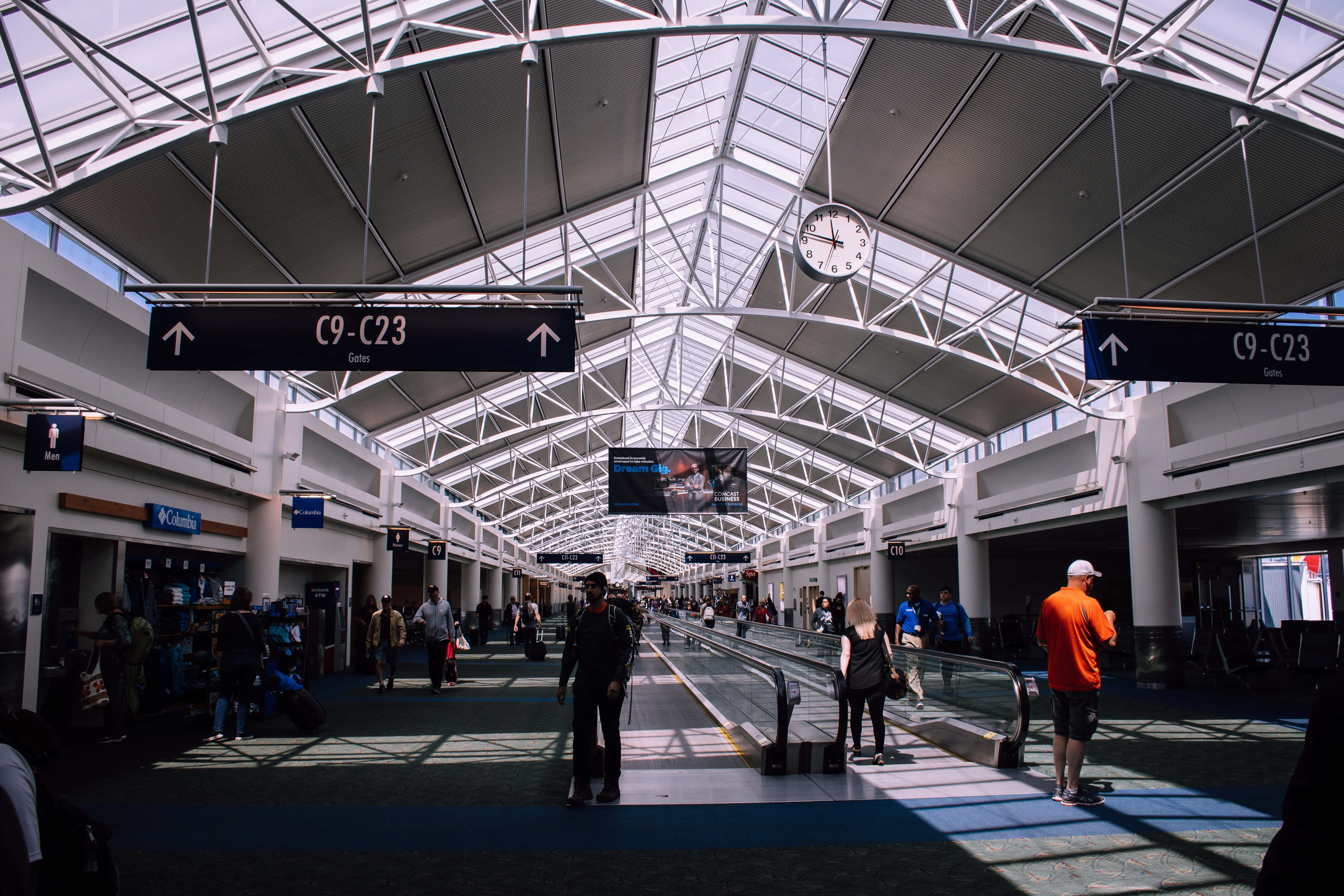 Airport 桌布 壁紙 — 陽光穿過玻璃天花板，照亮現代機場航站樓自動人行道上的旅客。