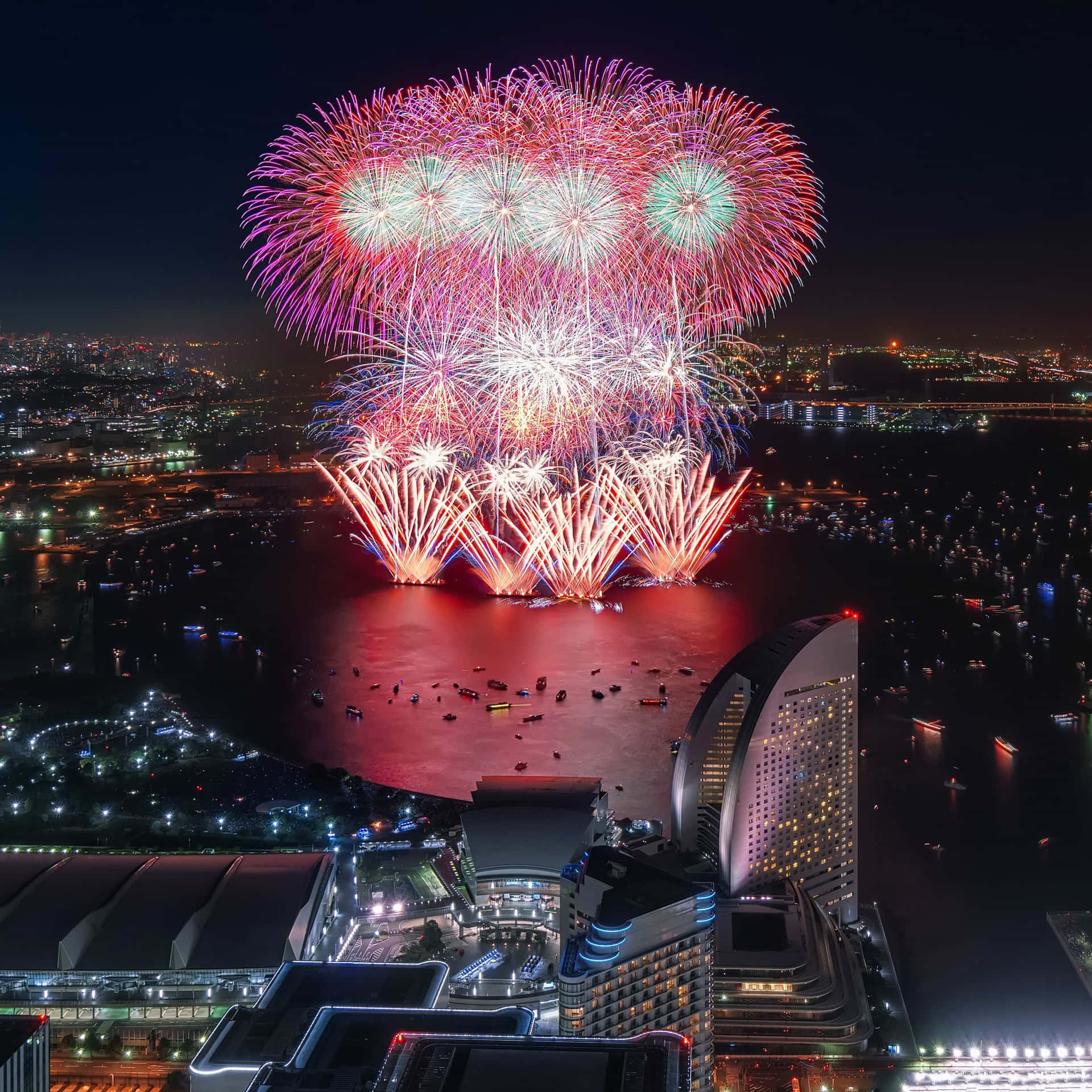 五彩繽紛的煙花在夜間的城市天際線和水面上綻放。
