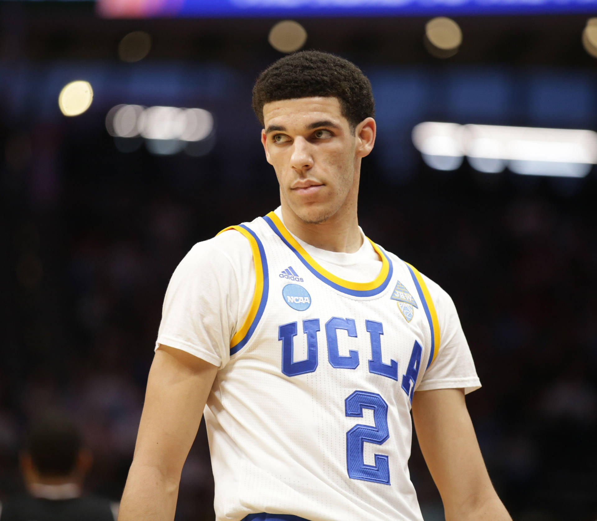 身穿白色、藍色和金色球衣的UCLA籃球運動員在球場上