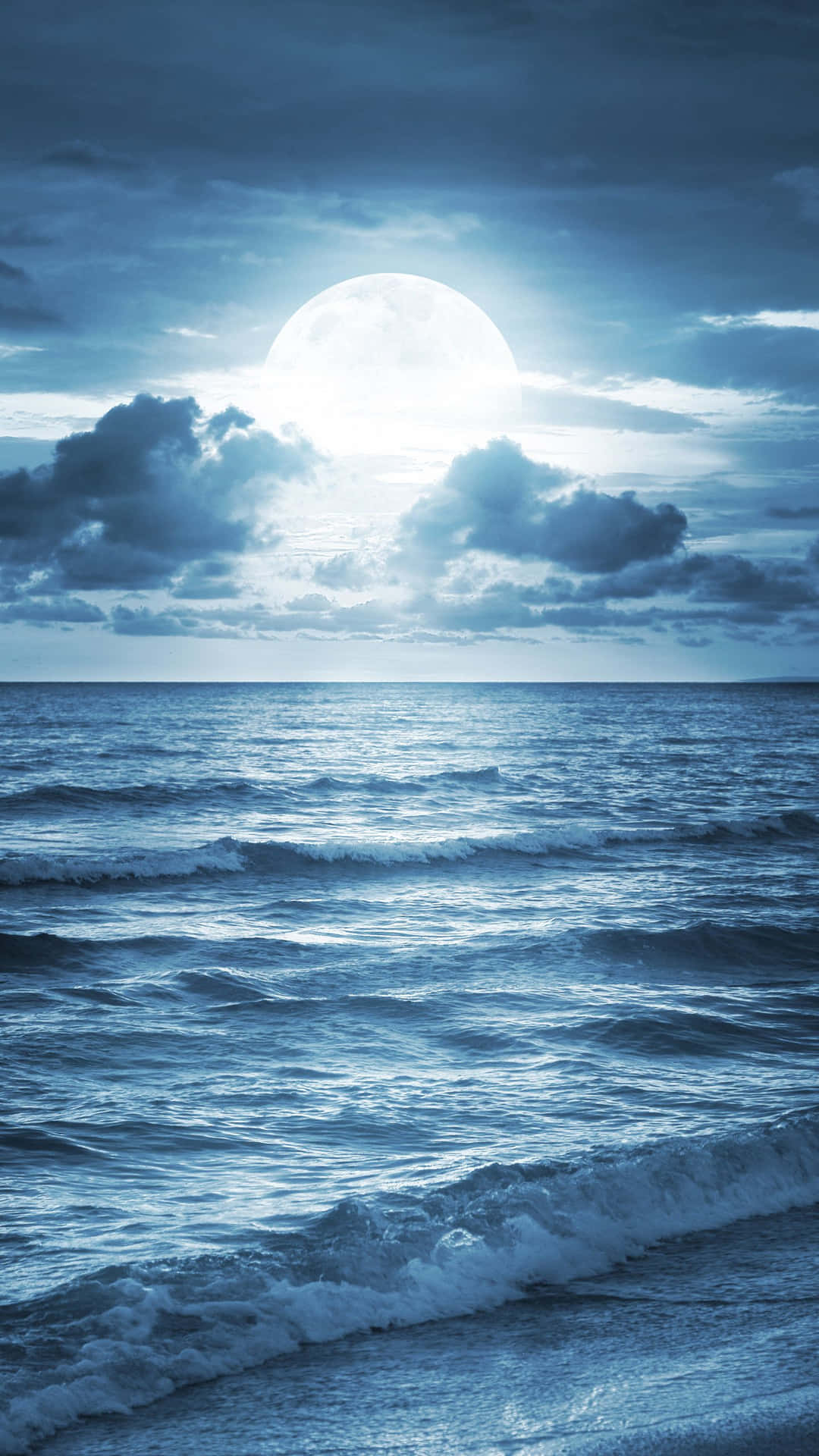 月光照亮了多雲夜空下翻騰的海浪。