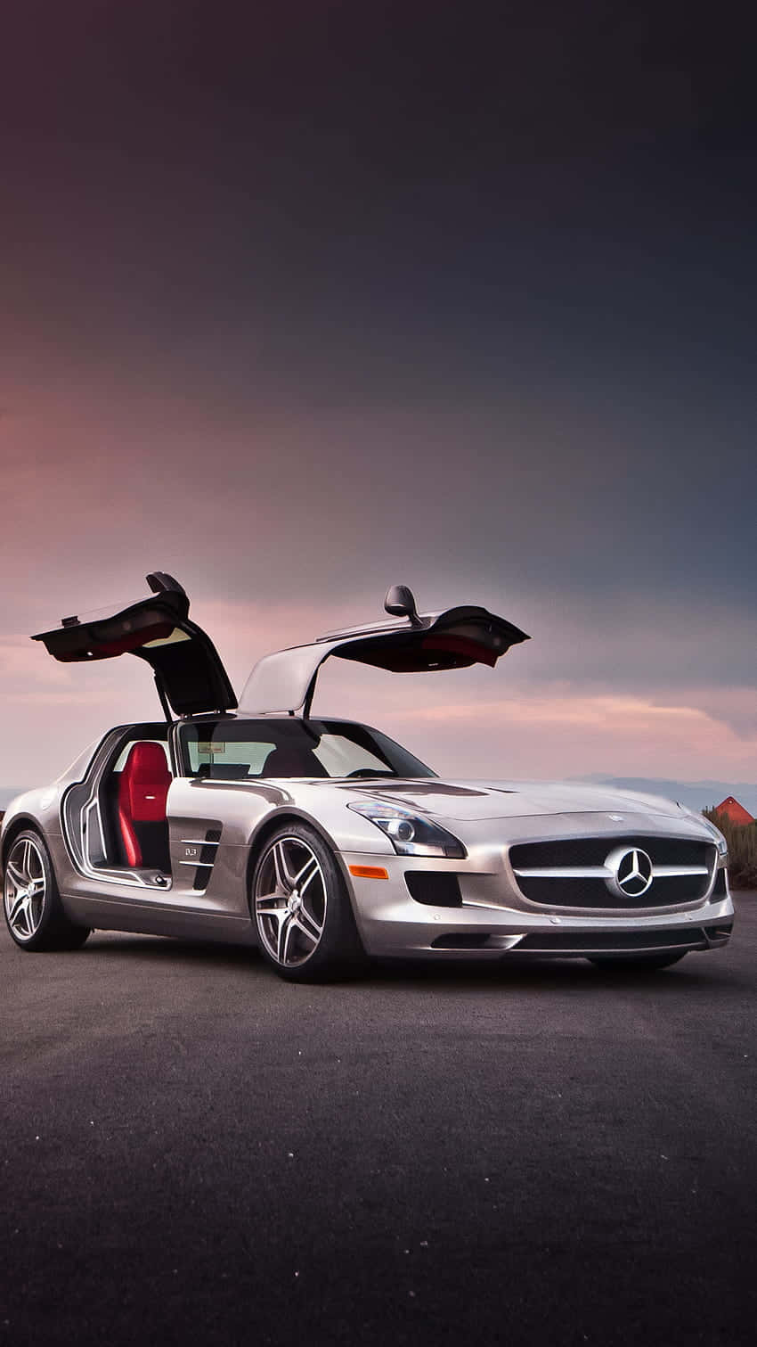 日落時分，銀色平治 SLS AMG 在道路上打開鷗翼車門。
