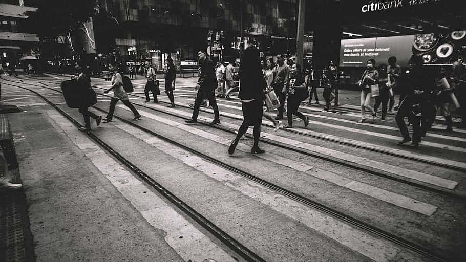 行人穿過有電車軌道的街道，在繁華的城市中。