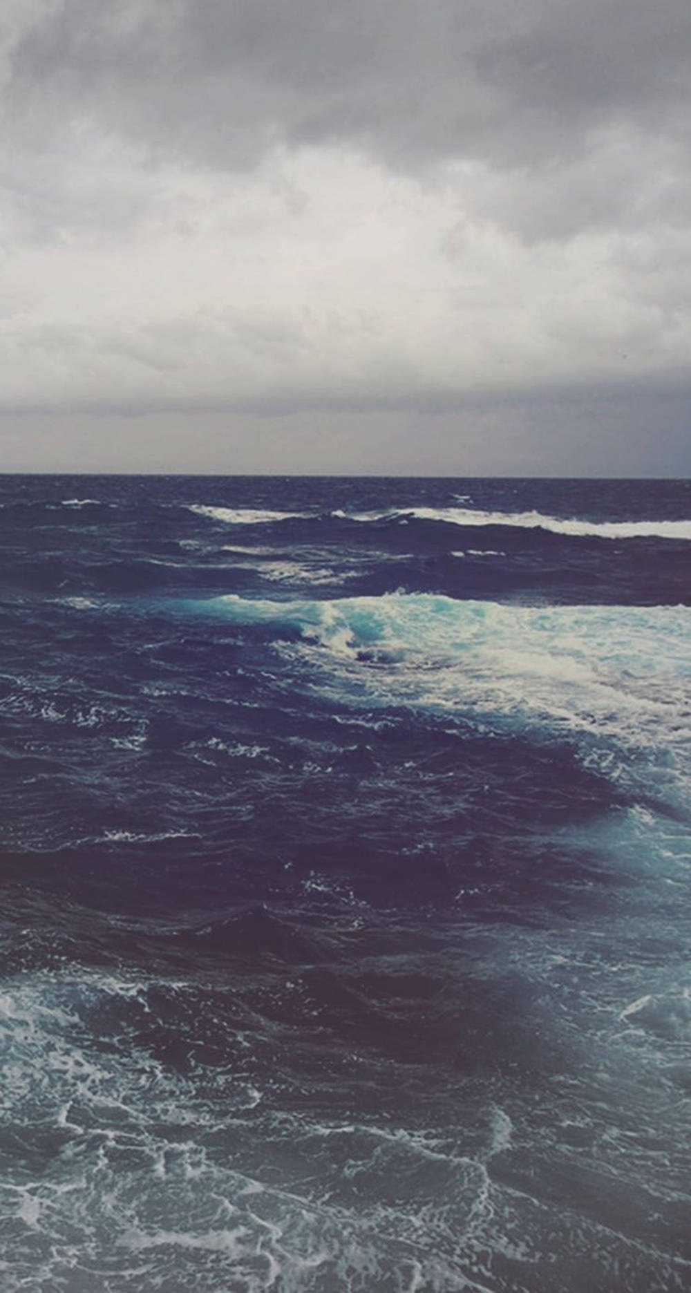 在暴風雨的灰色天空下，波濤洶湧的海浪。