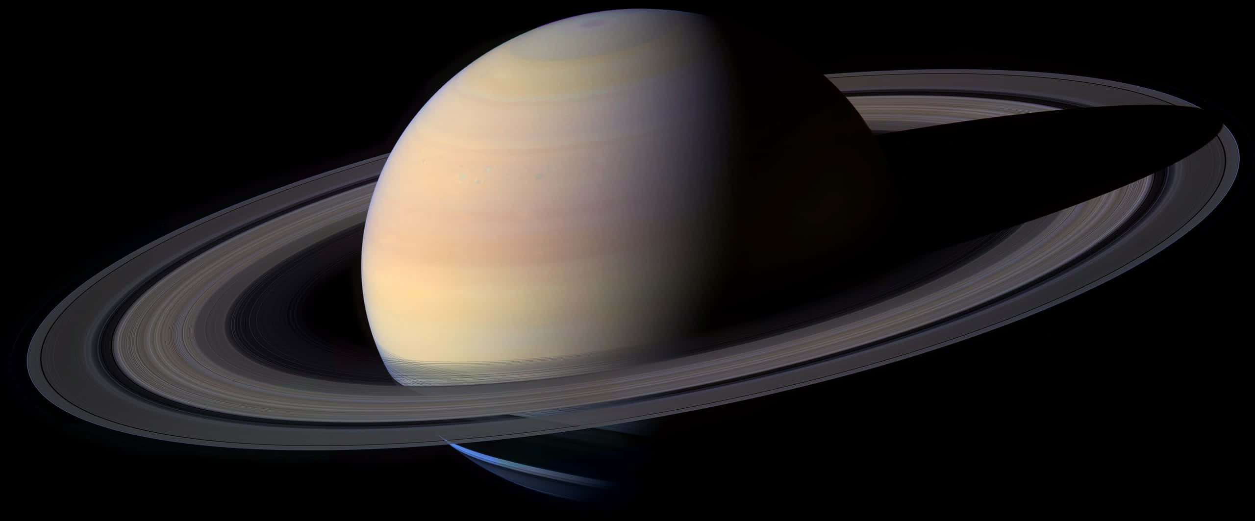 雄偉山景 壁紙 — 土星在黑色太空中柔和發光，其標誌性環在其條紋大氣層上投下銳利的陰影。