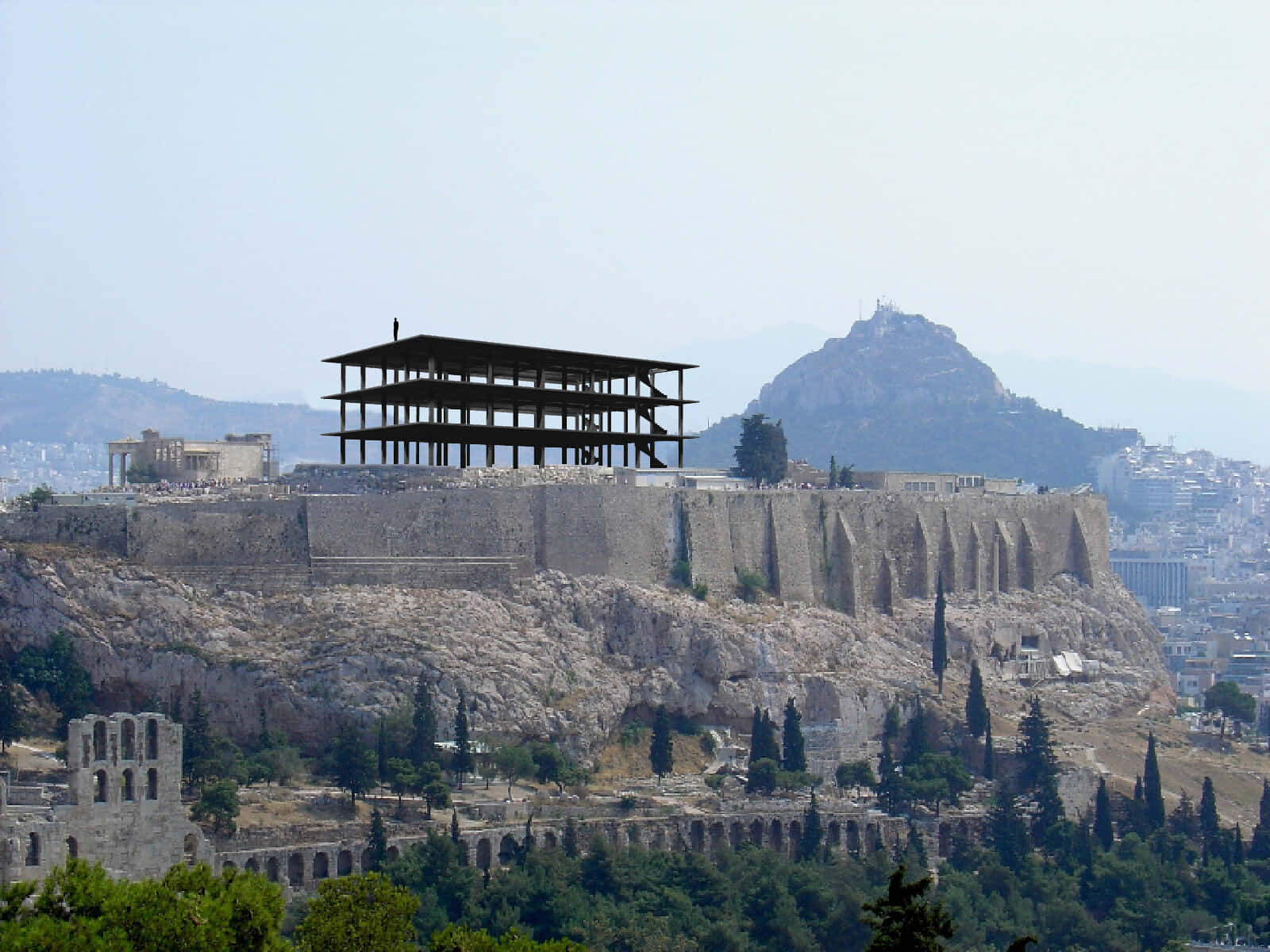 雅典山坡腳手架與利卡貝圖斯山 壁紙 — 古老雅典衛城遺跡，岩石山頂上現代保護結構，俯瞰霧氣籠罩下的雅典城市景觀。