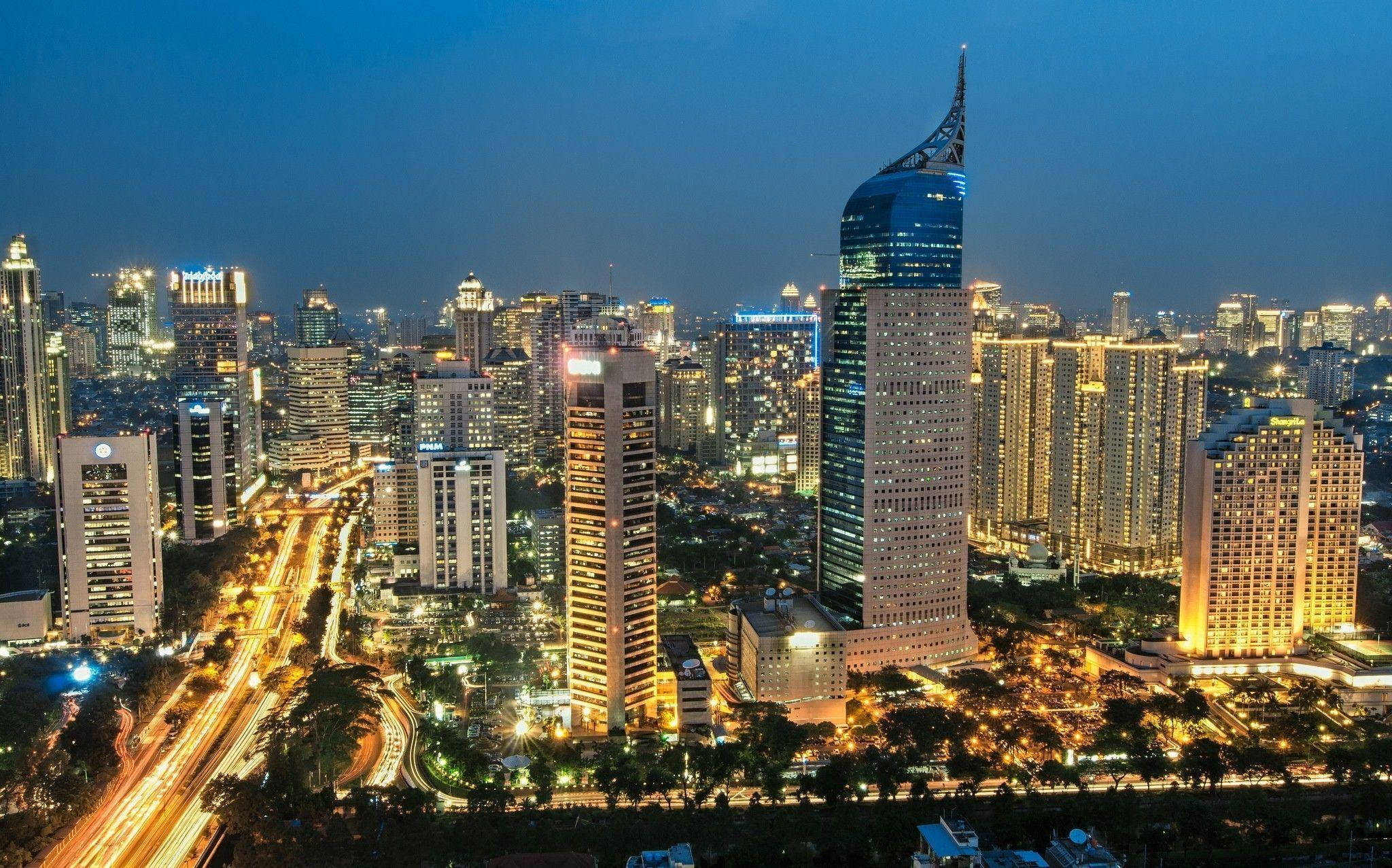 雅加達商業中心夜景 壁紙 — 黃昏時分繁忙城市天際線的鳥瞰圖，閃爍的摩天大樓和流動的交通燈光。