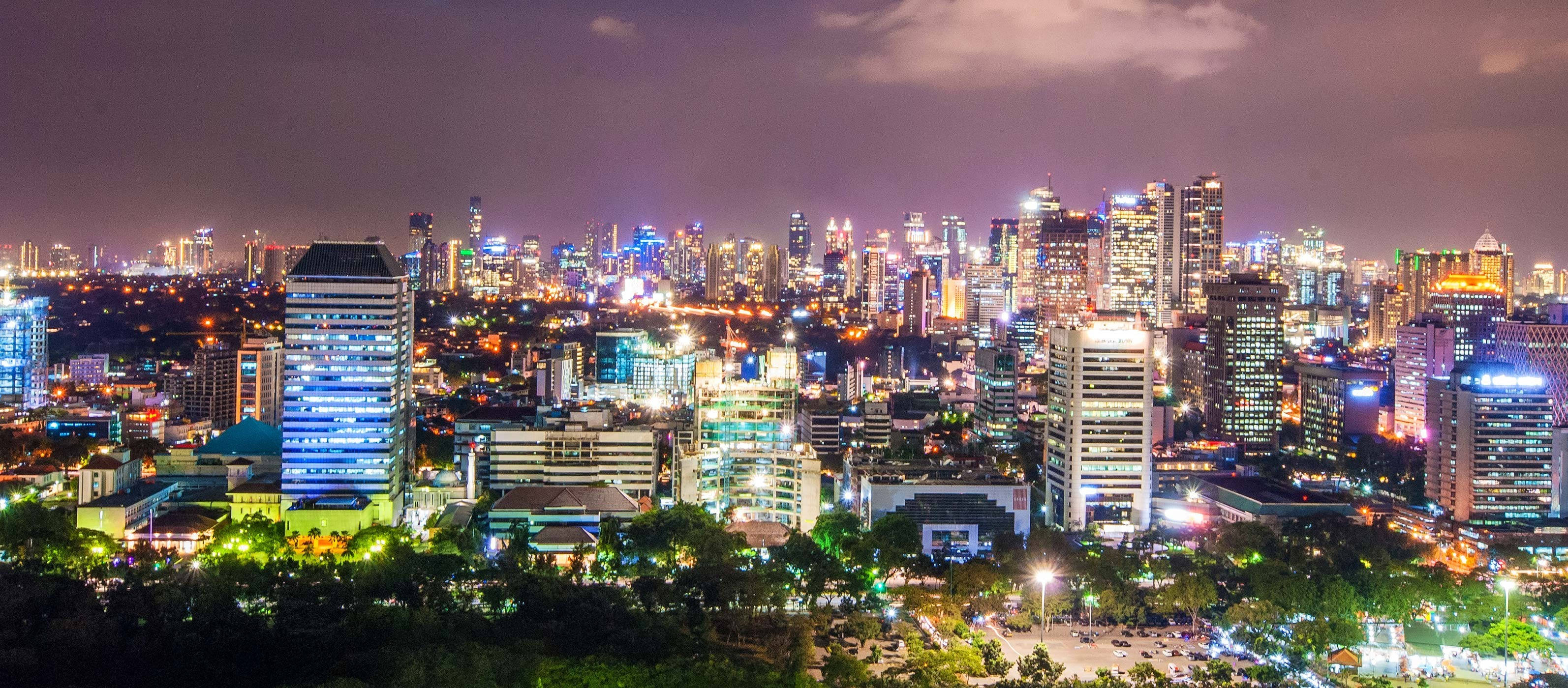 雅加達璀璨夜景 壁紙 — 令人眼花繚亂的夜景，高聳的摩天大樓在黑暗的天空中閃爍著霓虹燈光。