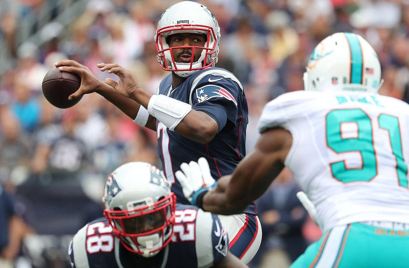 NFL四分衛在現場比賽中投擲橄欖球，防守球員逼近。