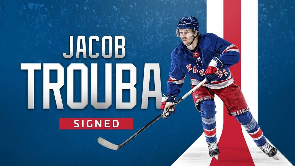 冰球運動員 Jacob Trouba 身穿 Rangers 球衣，手持球棍，帶有「Signed」文字。