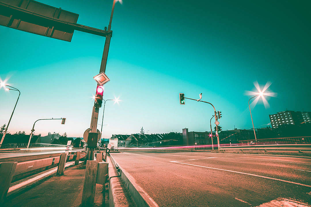 雅緻淺棕色道路 壁紙 — 黃昏時低角度城市街道，發光的交通燈和汽車燈光軌跡映襯著青綠色的天空。