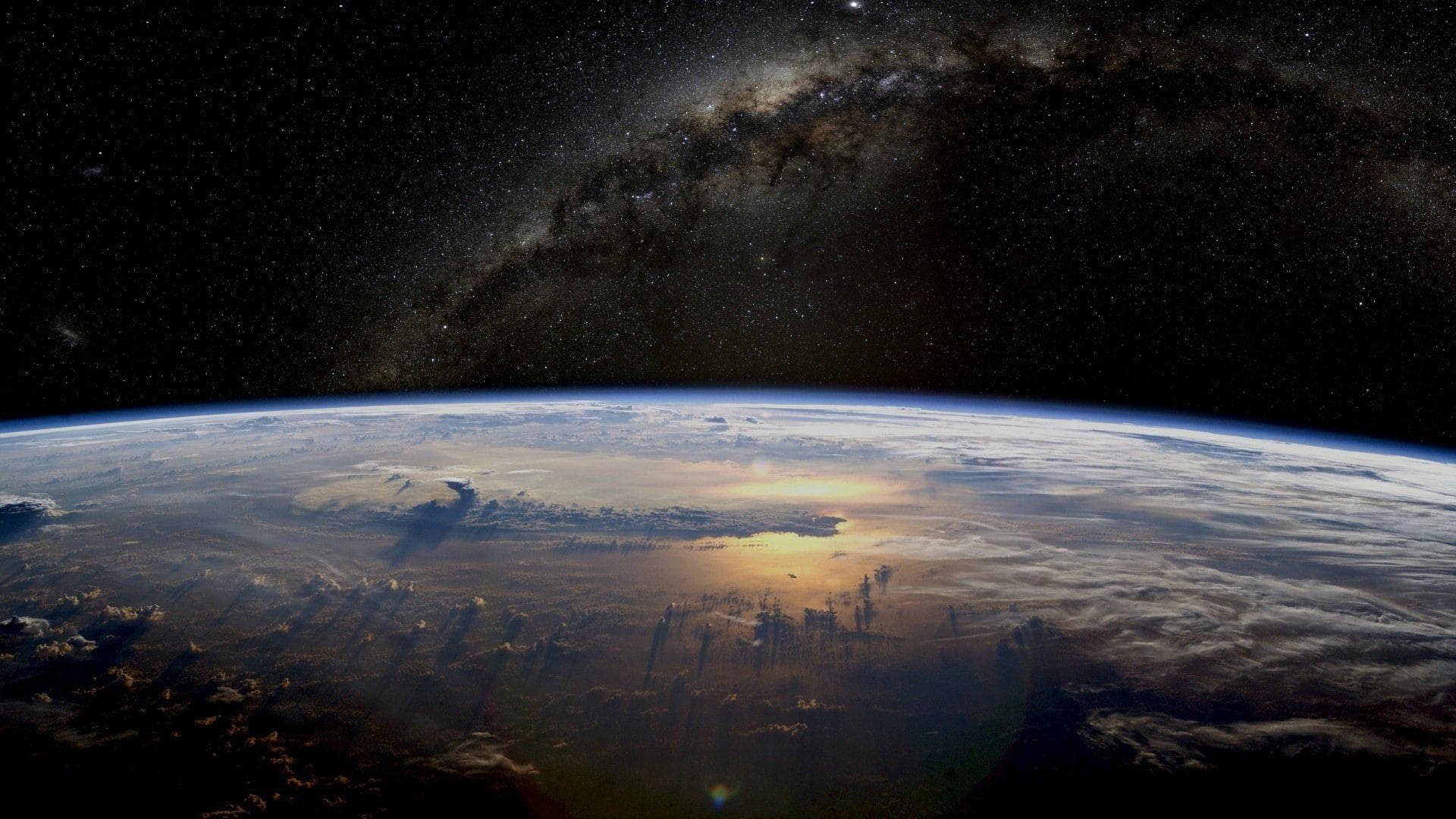 雅虎太空與地球 壁紙 — 地球在星空下彎曲，銀河在頭頂拱起，陽光在雲層上閃爍。