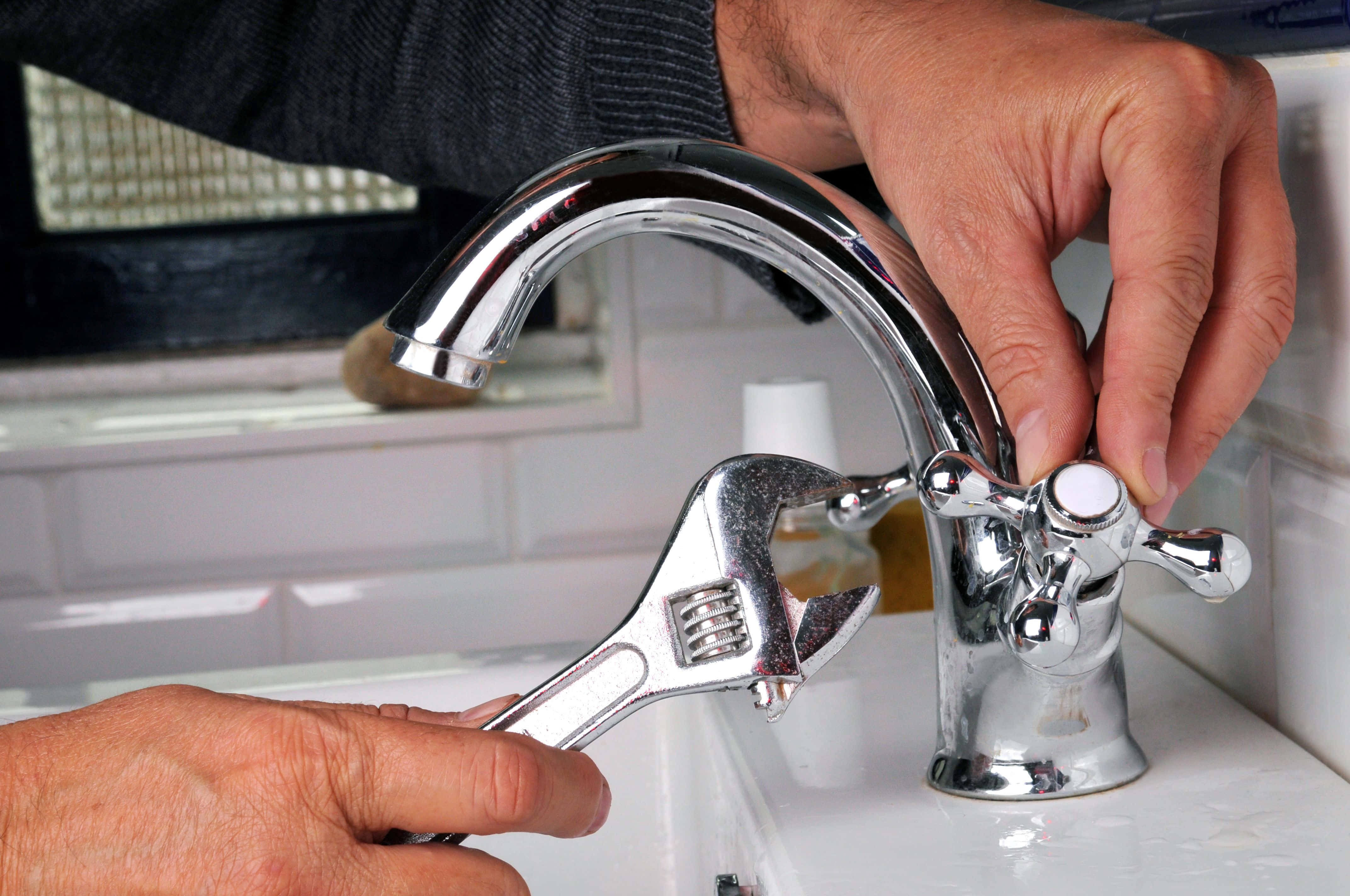 Plumbing 桌布 壁紙 — 雙手使用扳手修理白色洗手盆上閃亮鍍鉻水龍頭的近距離特寫。