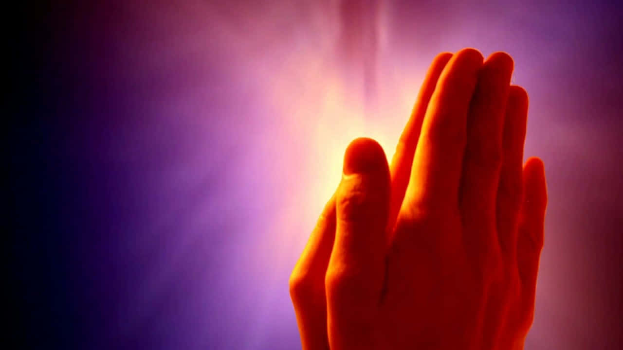 Praying 桌布 壁紙 — 雙手合十祈禱，在絢麗的紫色和橙色漸變背景中散發出溫暖的光芒。