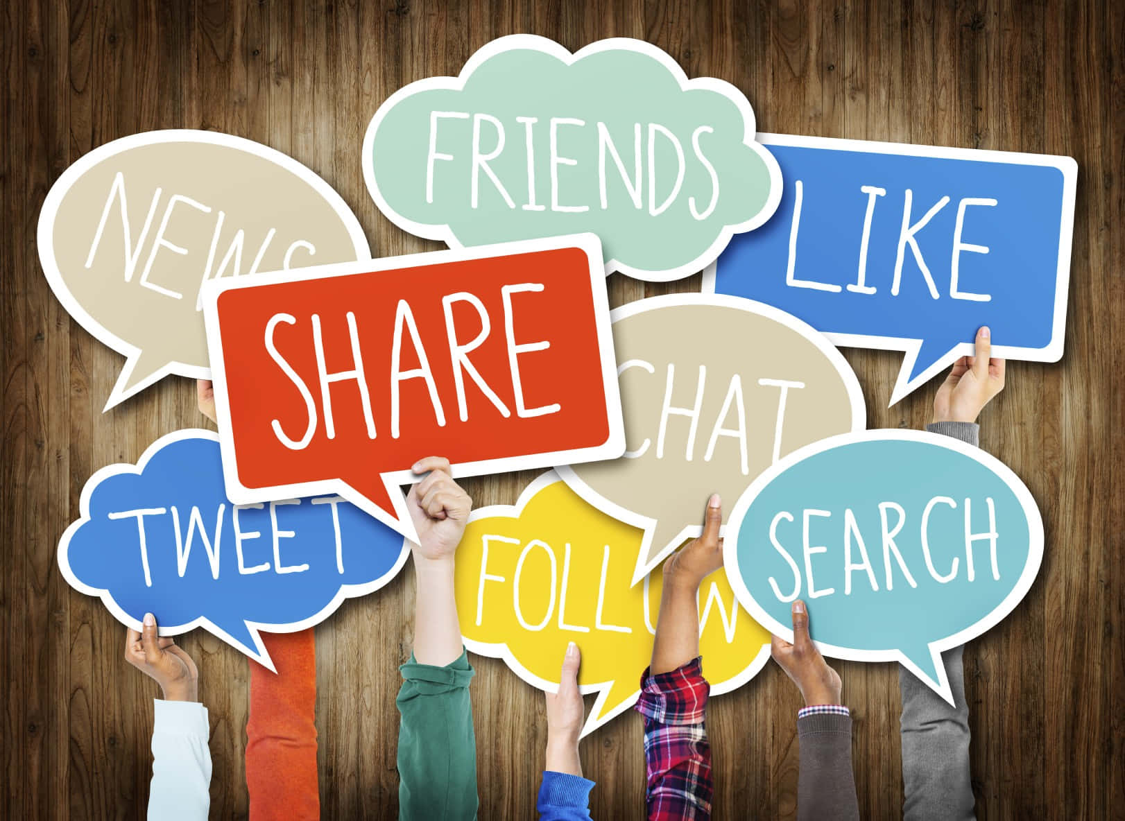 Social Media 桌布 壁紙 — 雙手在木質背景前拿著帶有社交媒體詞語的彩色對話氣泡。