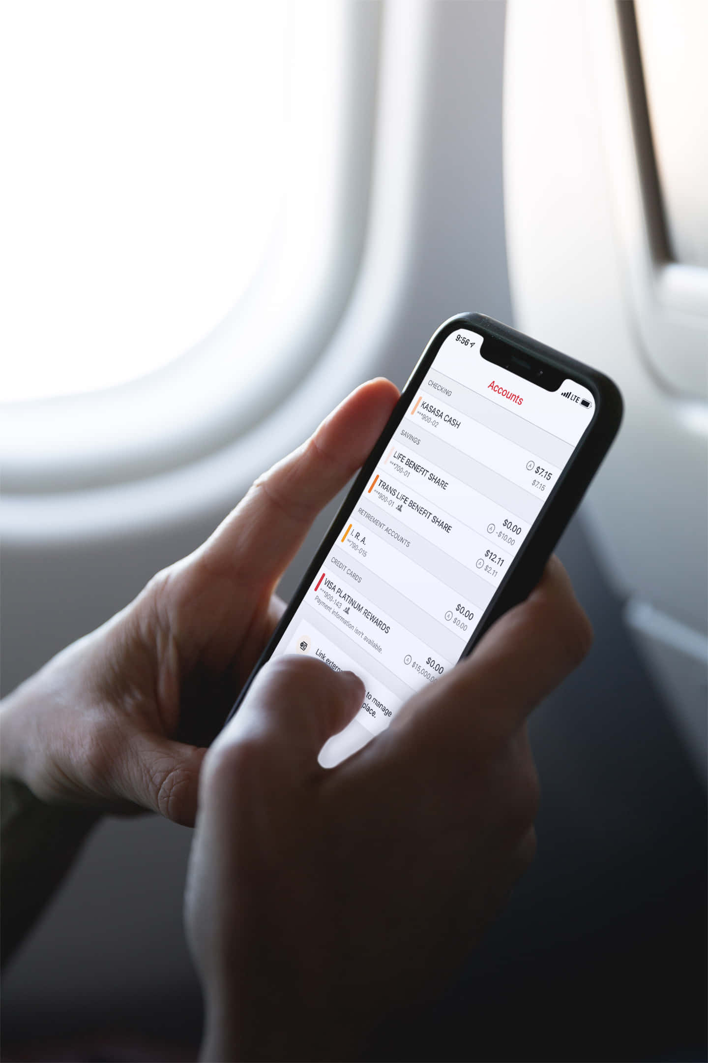 Mobile Banking 桌布 壁紙 — 雙手在飛機窗邊手持智能手機，顯示銀行賬戶，窗外陽光充足。