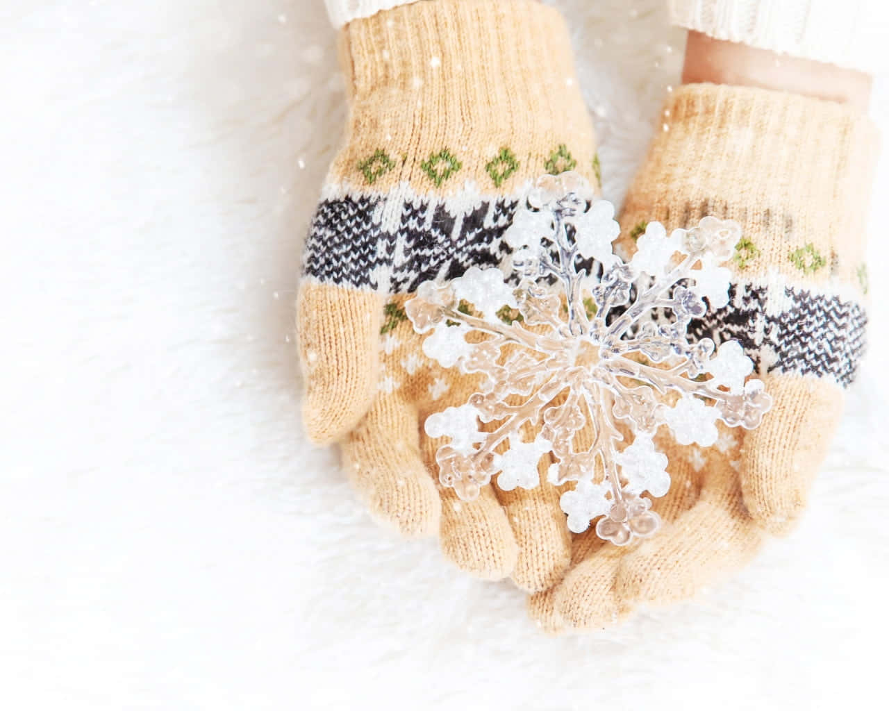 Mittens 桌布 壁紙 — 雙手戴著舒適的針織連指手套，捧著一個精緻的玻璃雪花，背景是柔軟的白色毛絨絨。