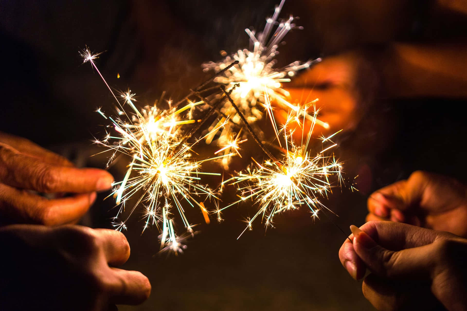 雙手握著煙花棒，用明亮的金色火花照亮夜晚。 — 新年動畫 壁紙