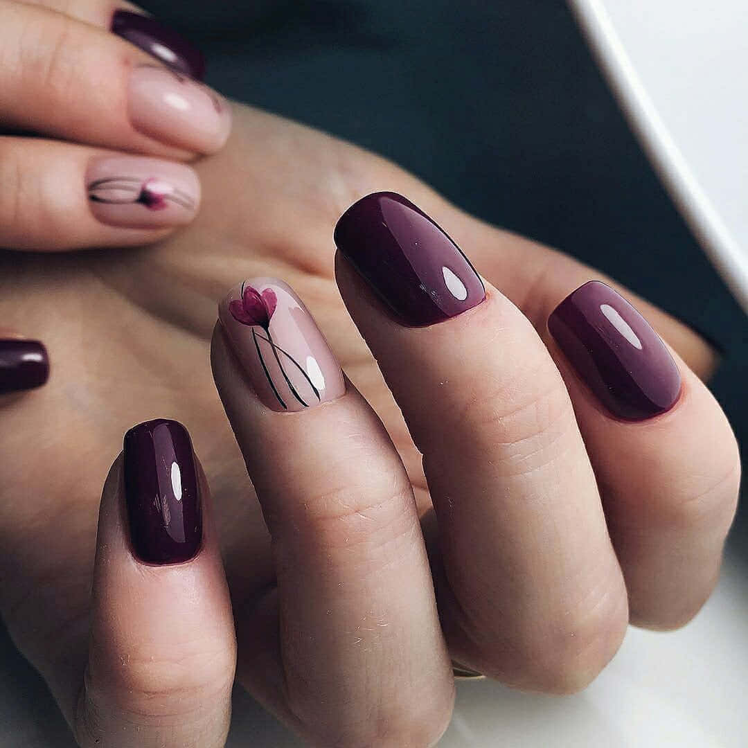 Spring Nails 桌布 壁紙 — 雙手特寫，帶有光澤的酒紅色指甲，裸色底色上點綴一朵精緻的粉紅花朵設計。