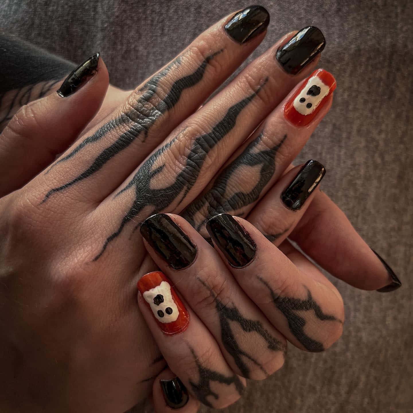 Halloween Nail Art 桌布 壁紙 — 雙手特寫，帶有黑色紋身和萬聖節主題的鬼魂指甲藝術在兩根手指上。