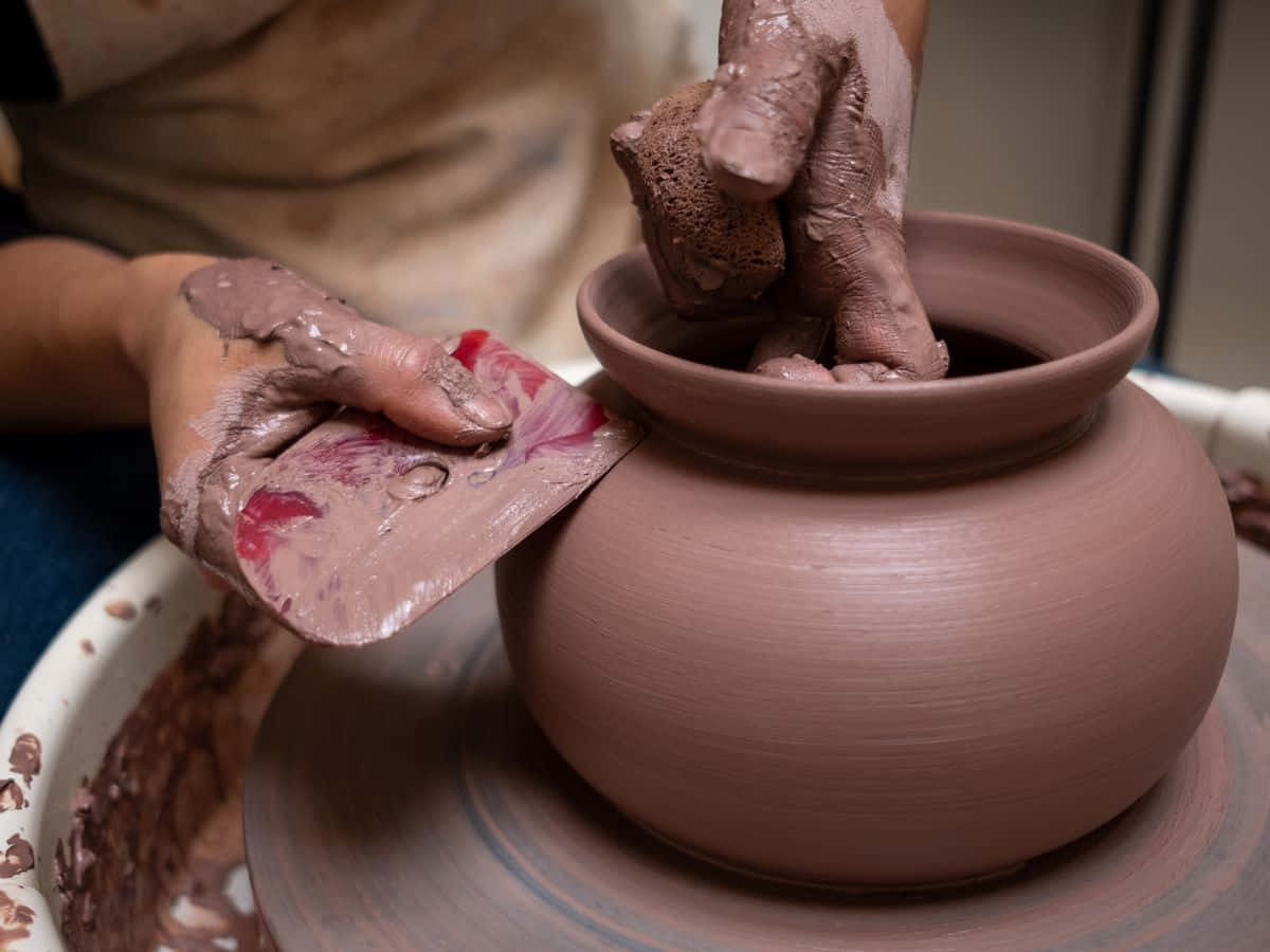 Ceramic 桌布 壁紙 — 雙手用木製肋條工具在陶輪上將濕粘土塑造成圓形容器的特寫。