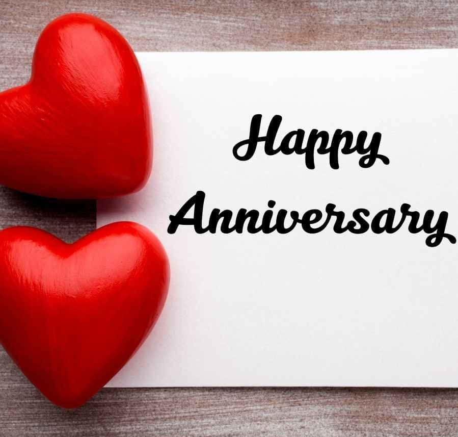 兩個紅色心形旁邊有一張寫著 Happy Anniversary 的卡片。