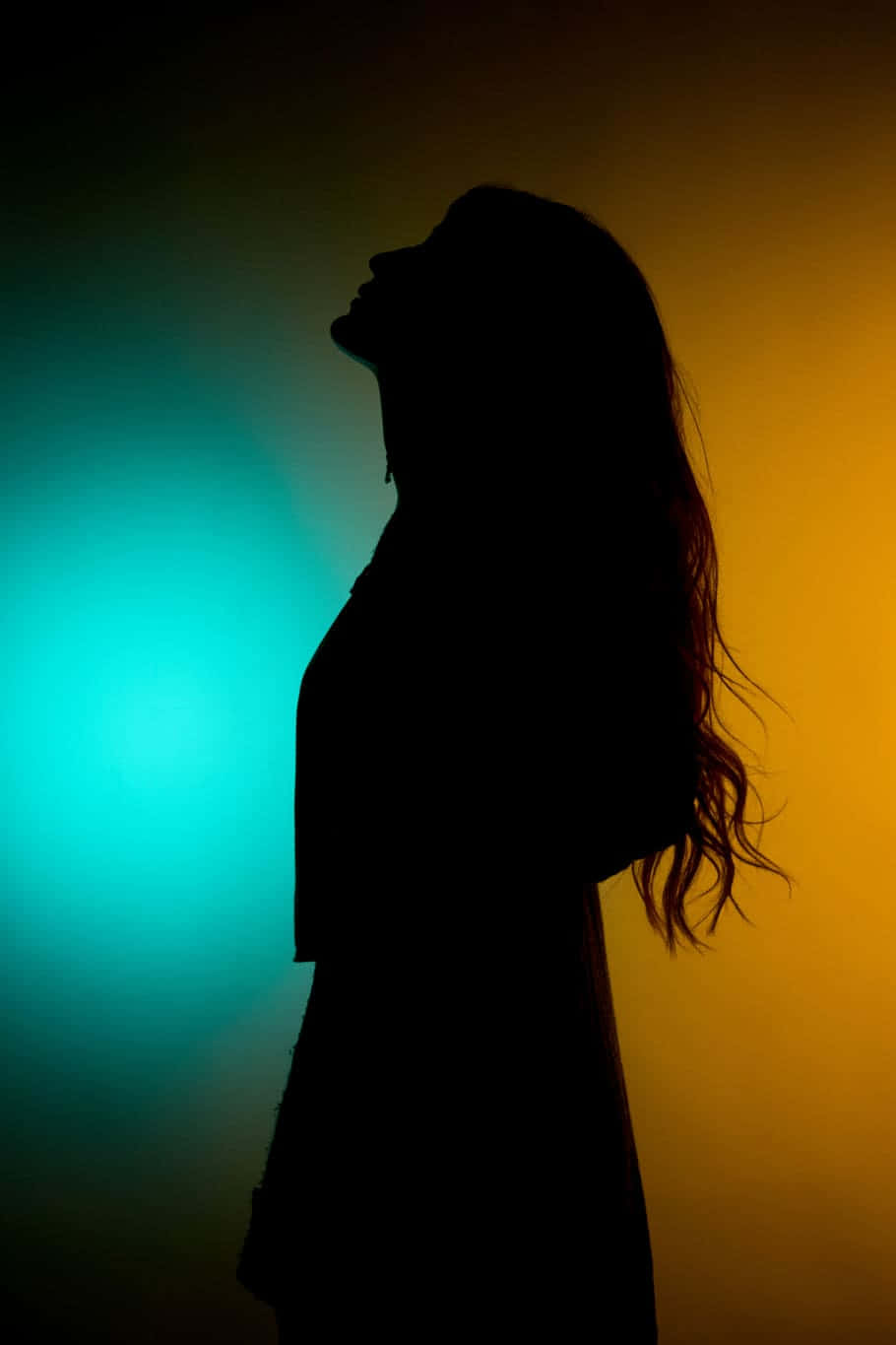 一個女人在青綠色和橙色漸變背景下的剪影。