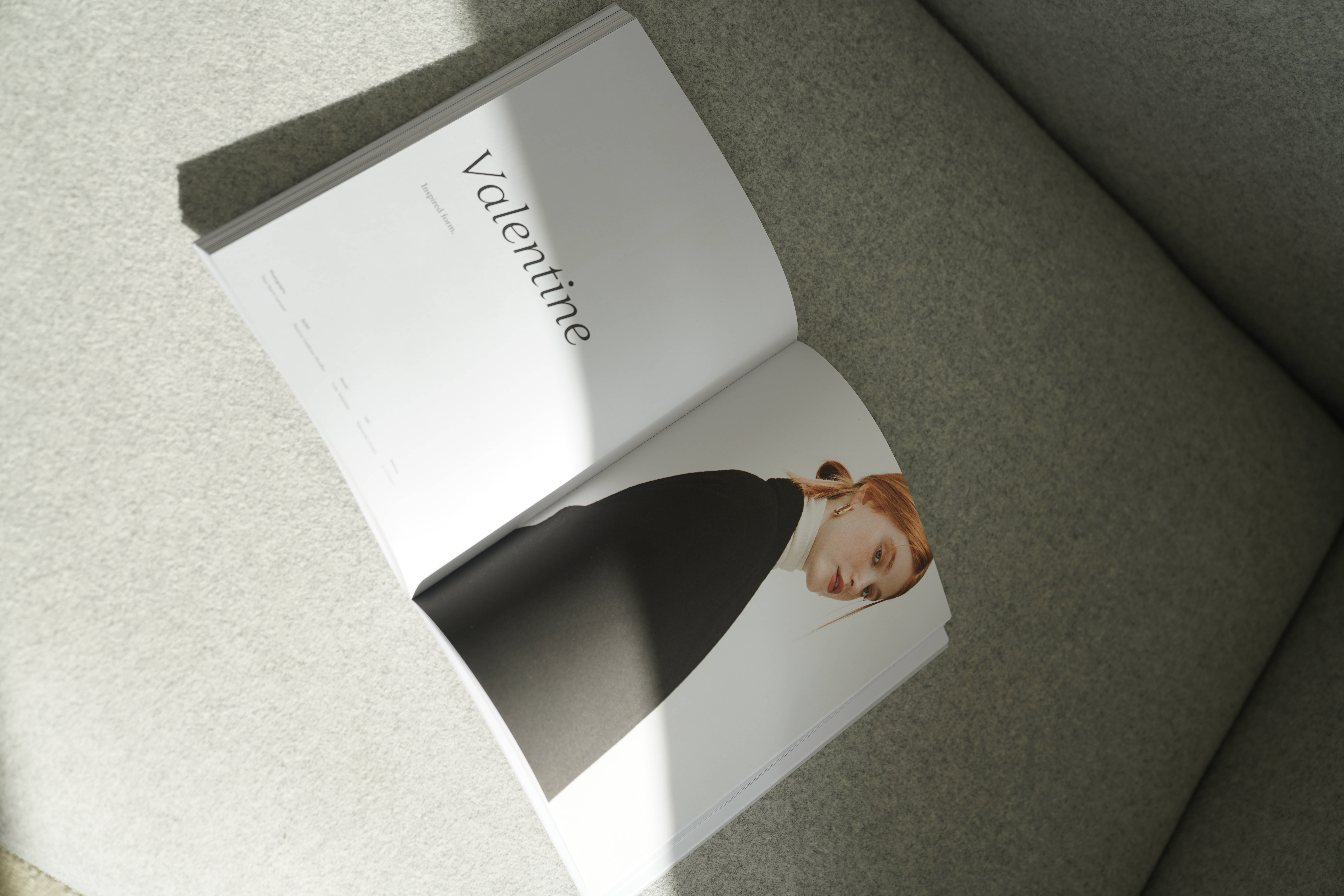 雜誌與女模特 壁紙 — 一本打開的時尚雜誌《Valentine》放在灰色沙發上，柔和自然光投射出陰影。