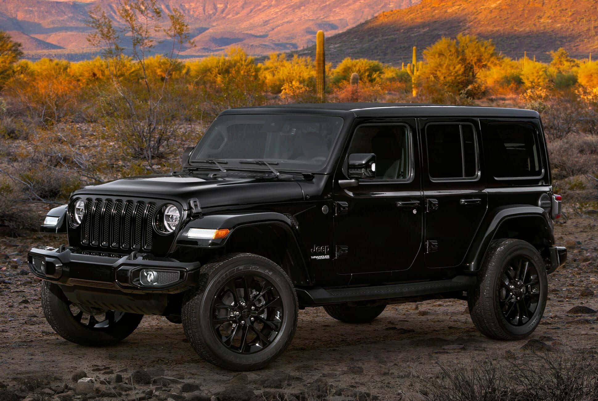 離開道路，踏上越野小徑，駕駛Jeep Wrangler 壁紙 — 一架型格黑色Jeep Wrangler在陽光明媚的沙漠景觀中矗立，四周有金色灌木和遠山。