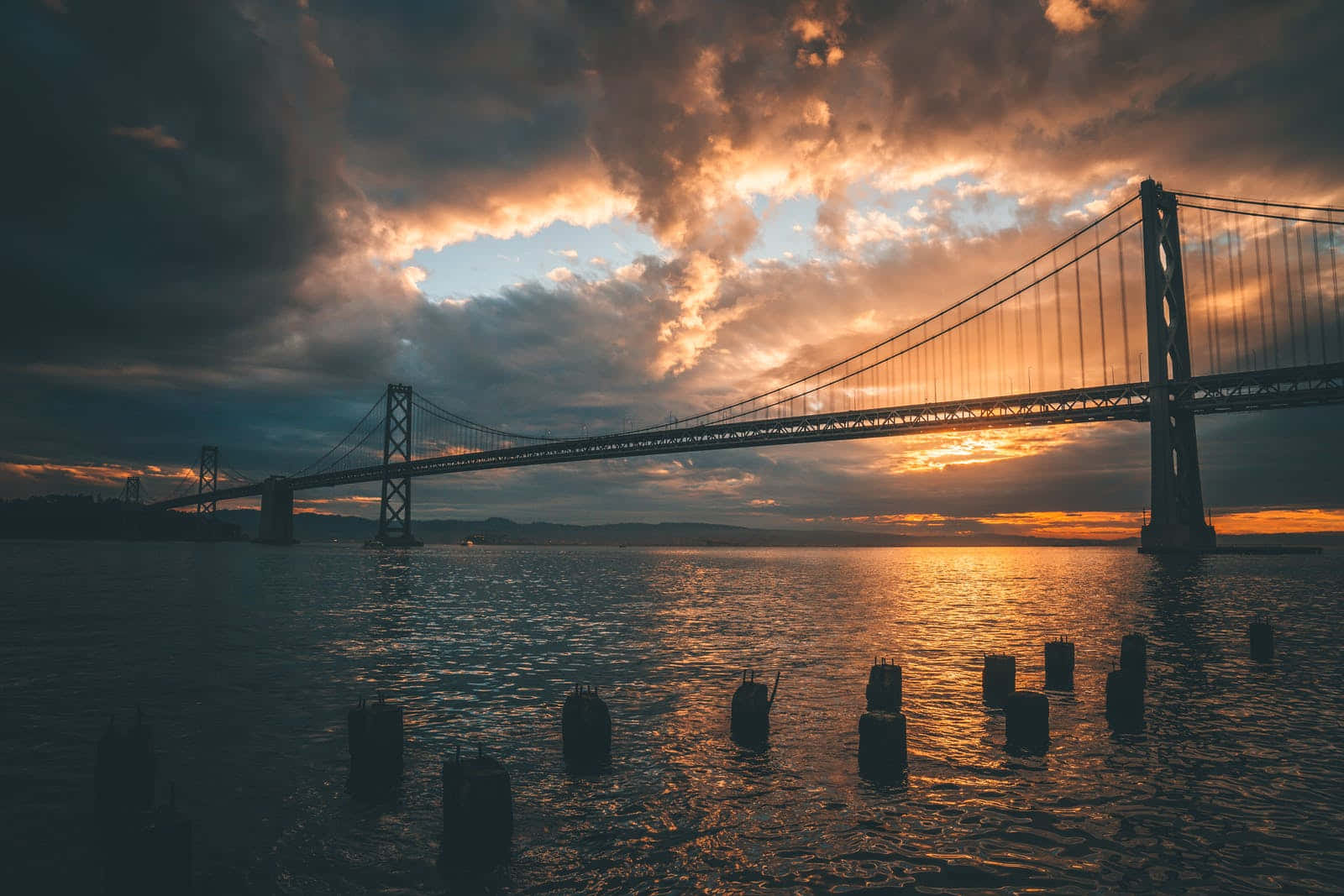 金色夕陽下，帶有戲劇性烏雲的水上吊橋