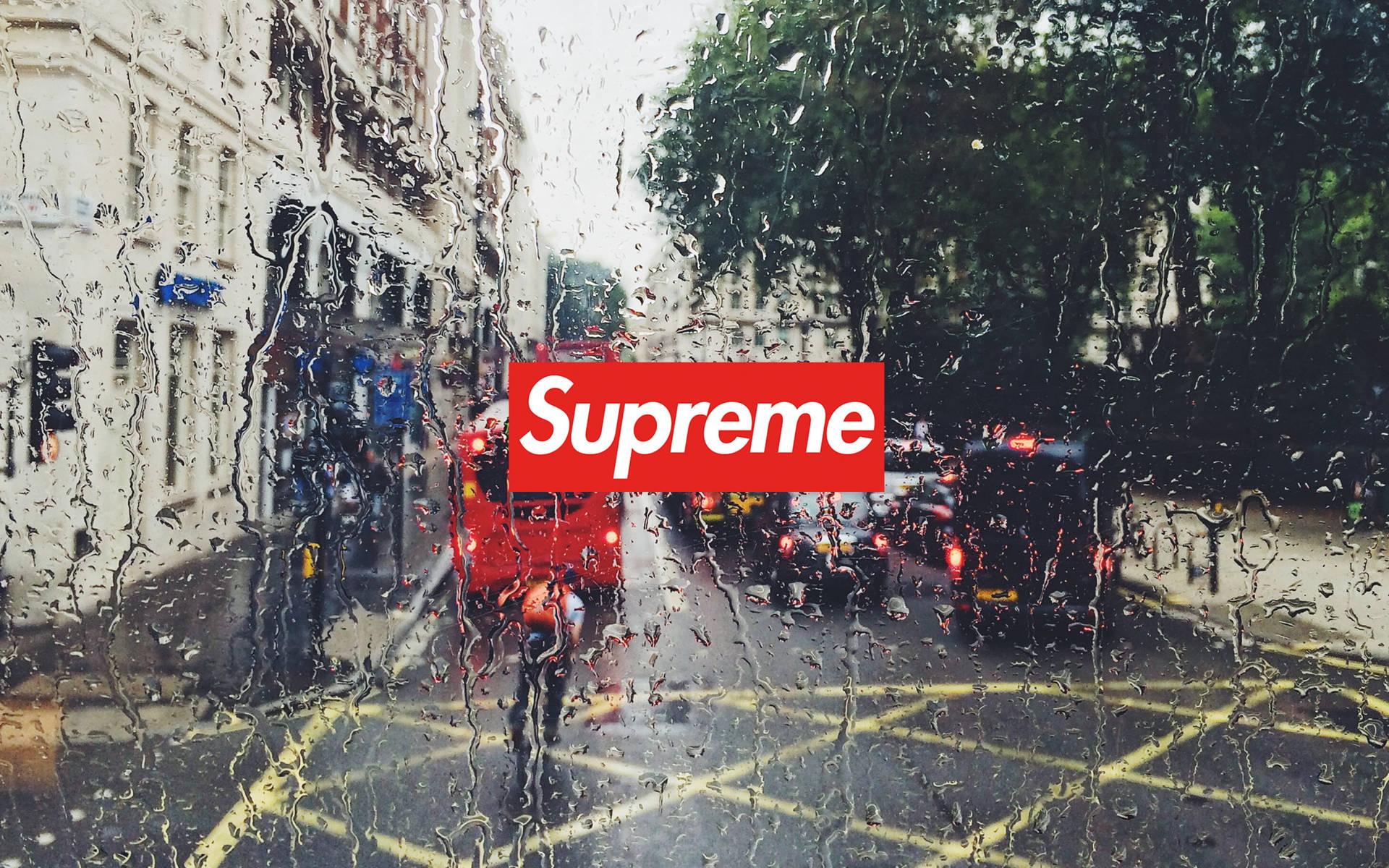 汽車車窗上的雨滴，望向城市交通中的紅色雙層巴士和Supreme標誌。