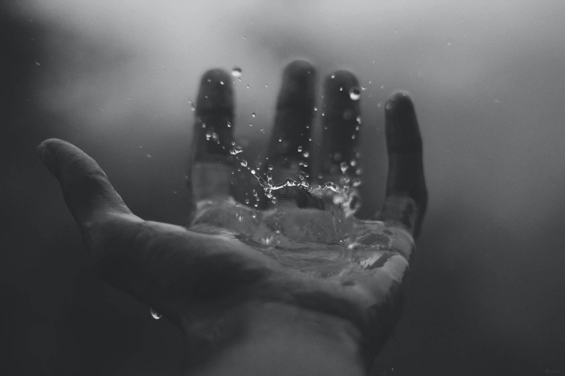 手浸入水中，水滴以灰度向上飛濺。