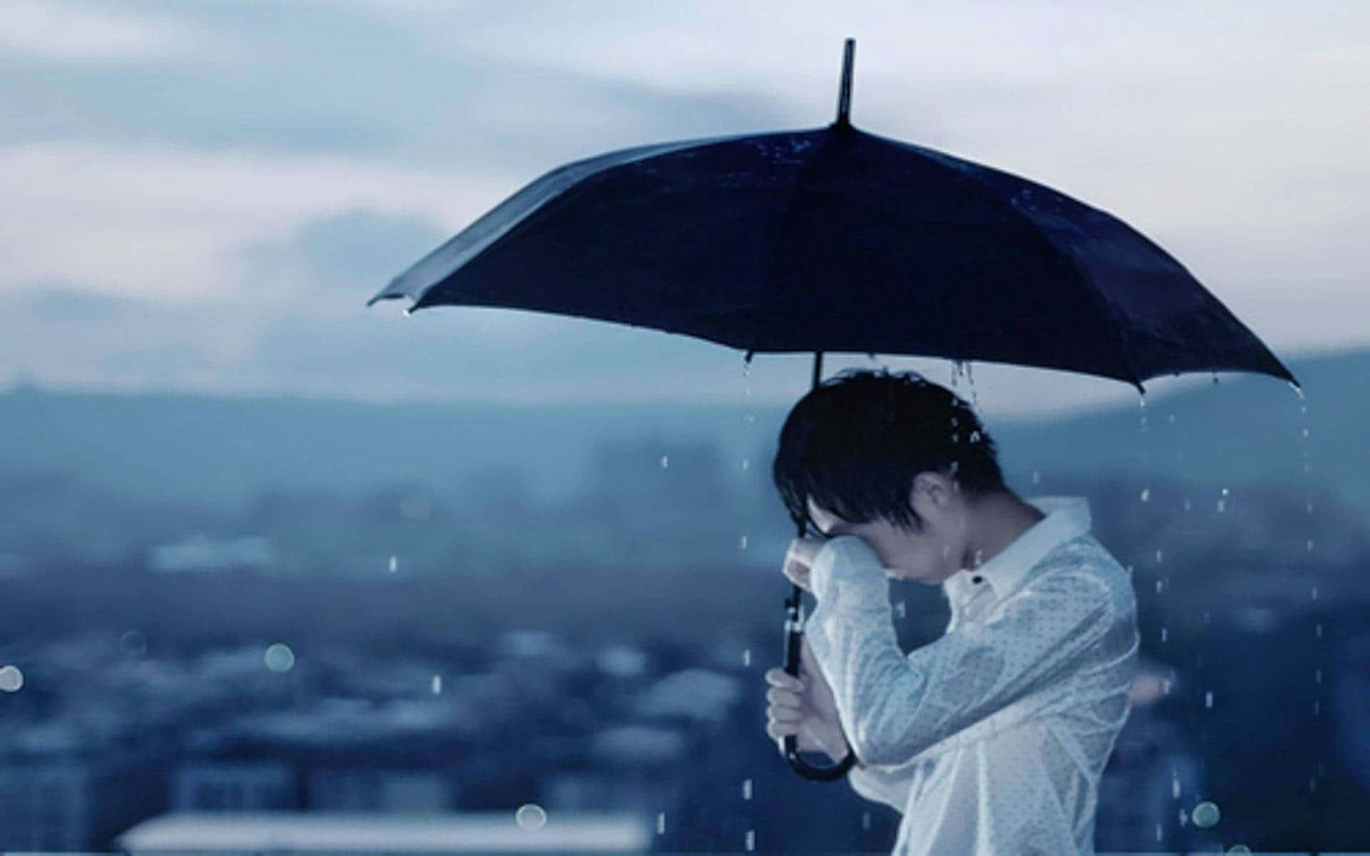 在雨中城市景觀中手持黑色雨傘低頭看的人