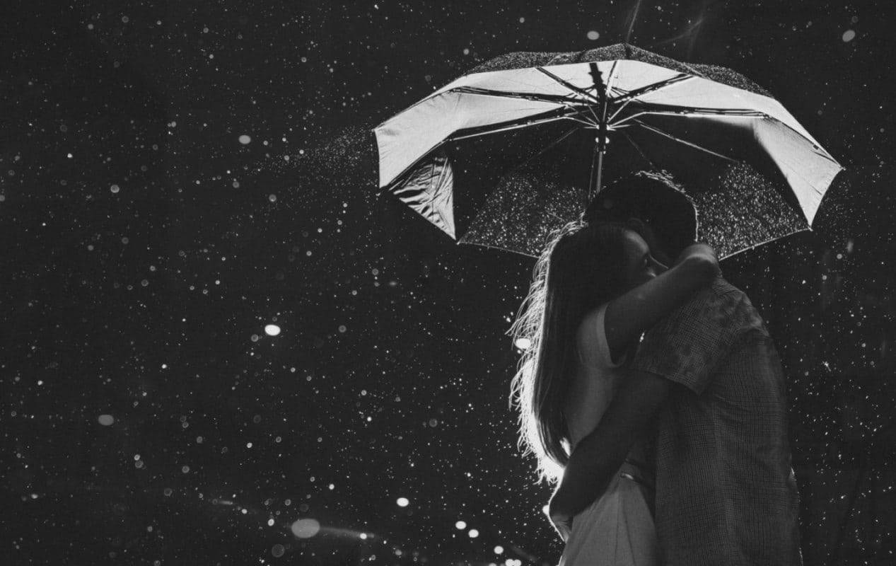 一對情侶在夜雨中共享一把雨傘。
